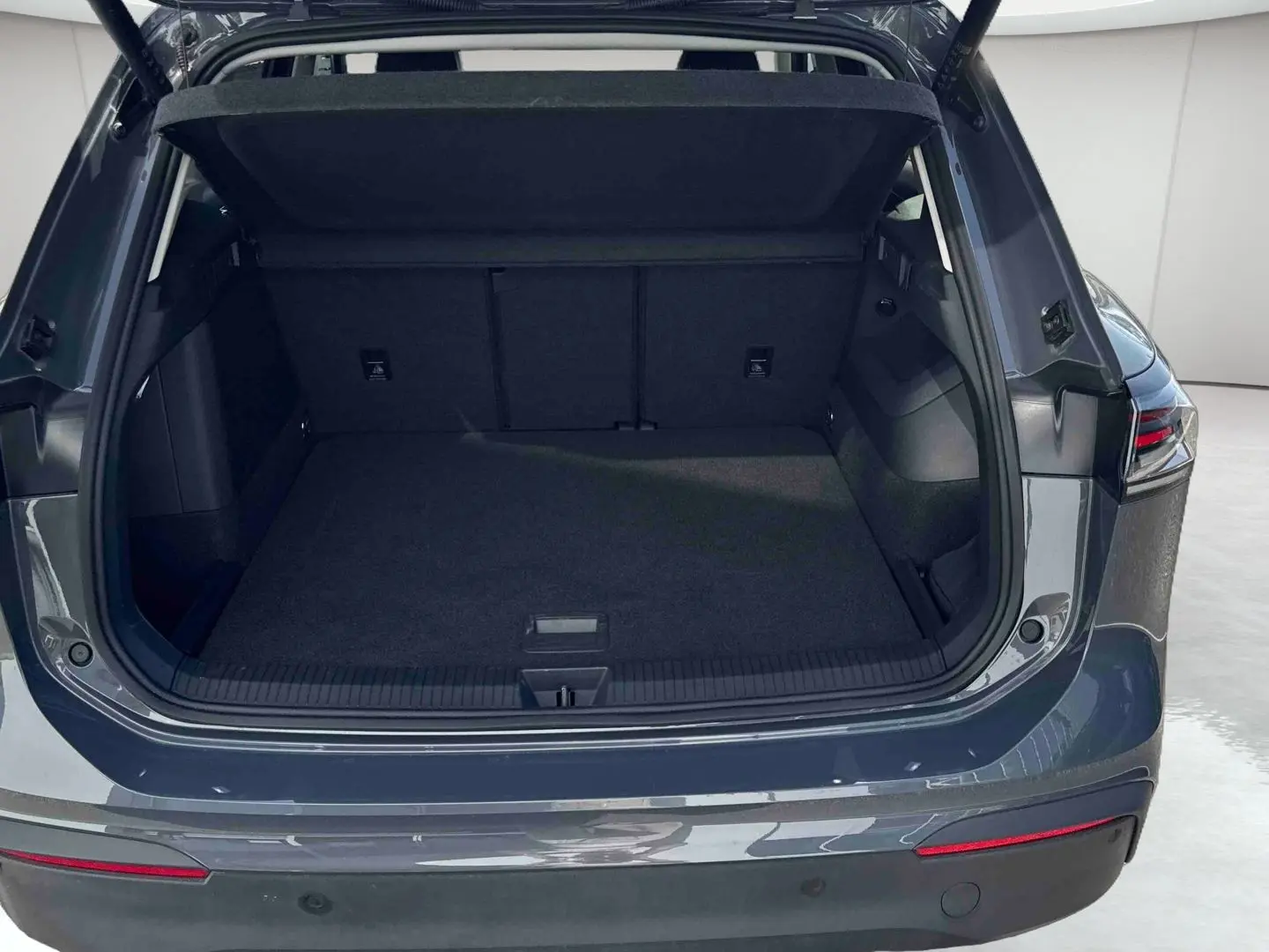Coffre ouvert vu de l'arrière d'un Volkswagen Tiguan 2025 gris, avec feux arrière LED 3D visibles.