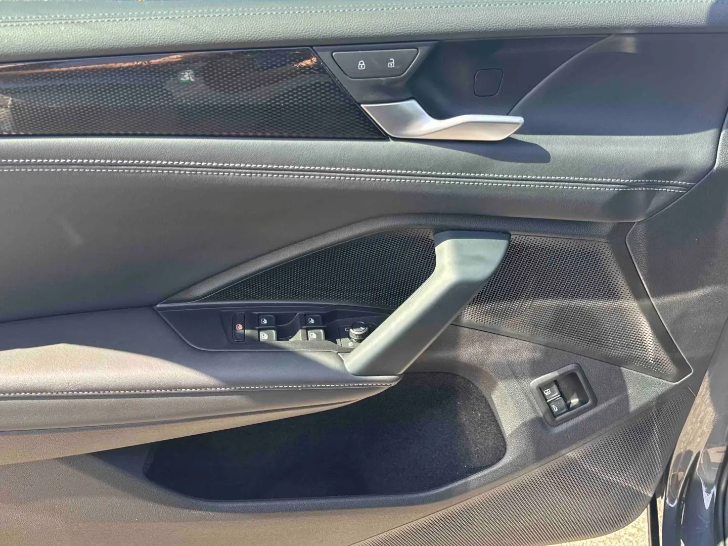 Intérieur côté conducteur du Volkswagen Tiguan 2025 gris, montrant la portière avec commandes électriques et poignée argentée.