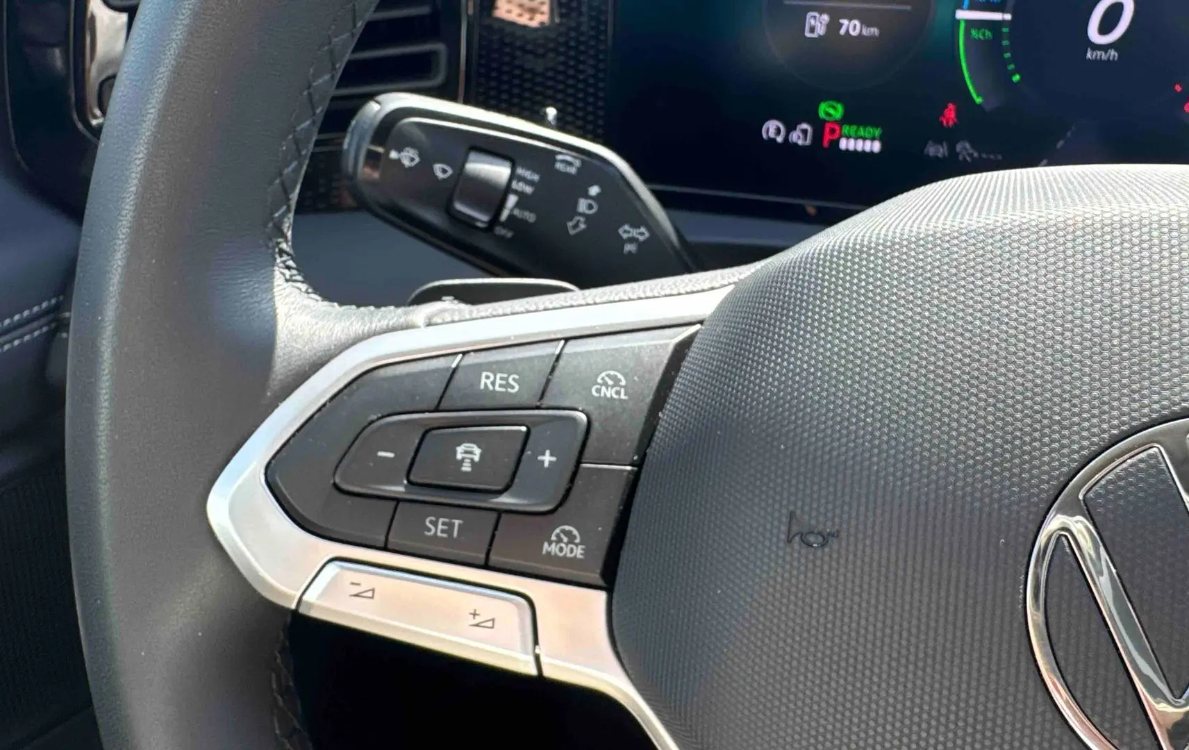 Gros plan sur le volant noir du Volkswagen Tiguan eHybrid 2025, montrant les commandes de régulateur de vitesse à gauche.