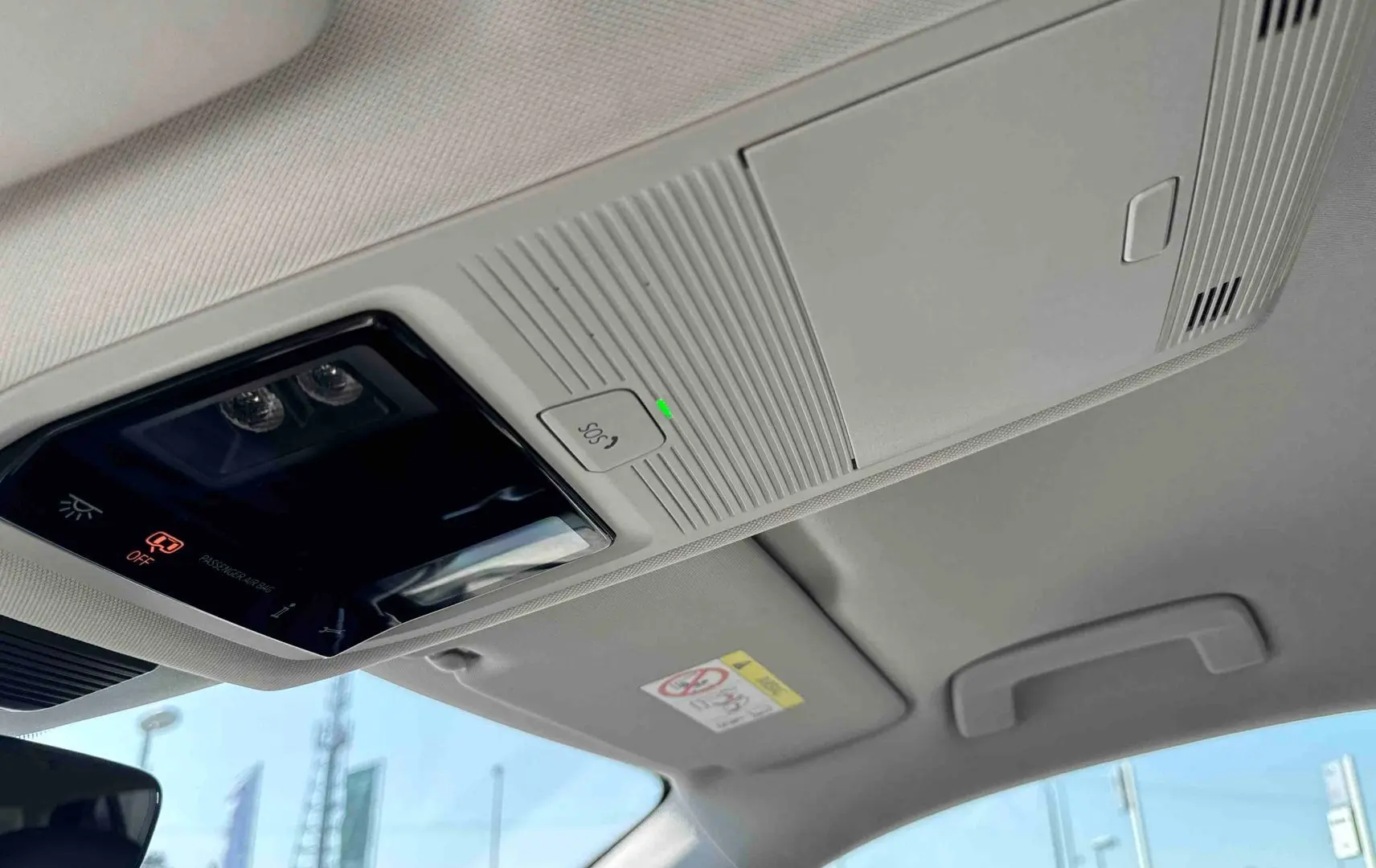 Plafonnier intérieur avec commandes SOS et éclairage, vue du toit clair du Volkswagen Tiguan gris 2025.
