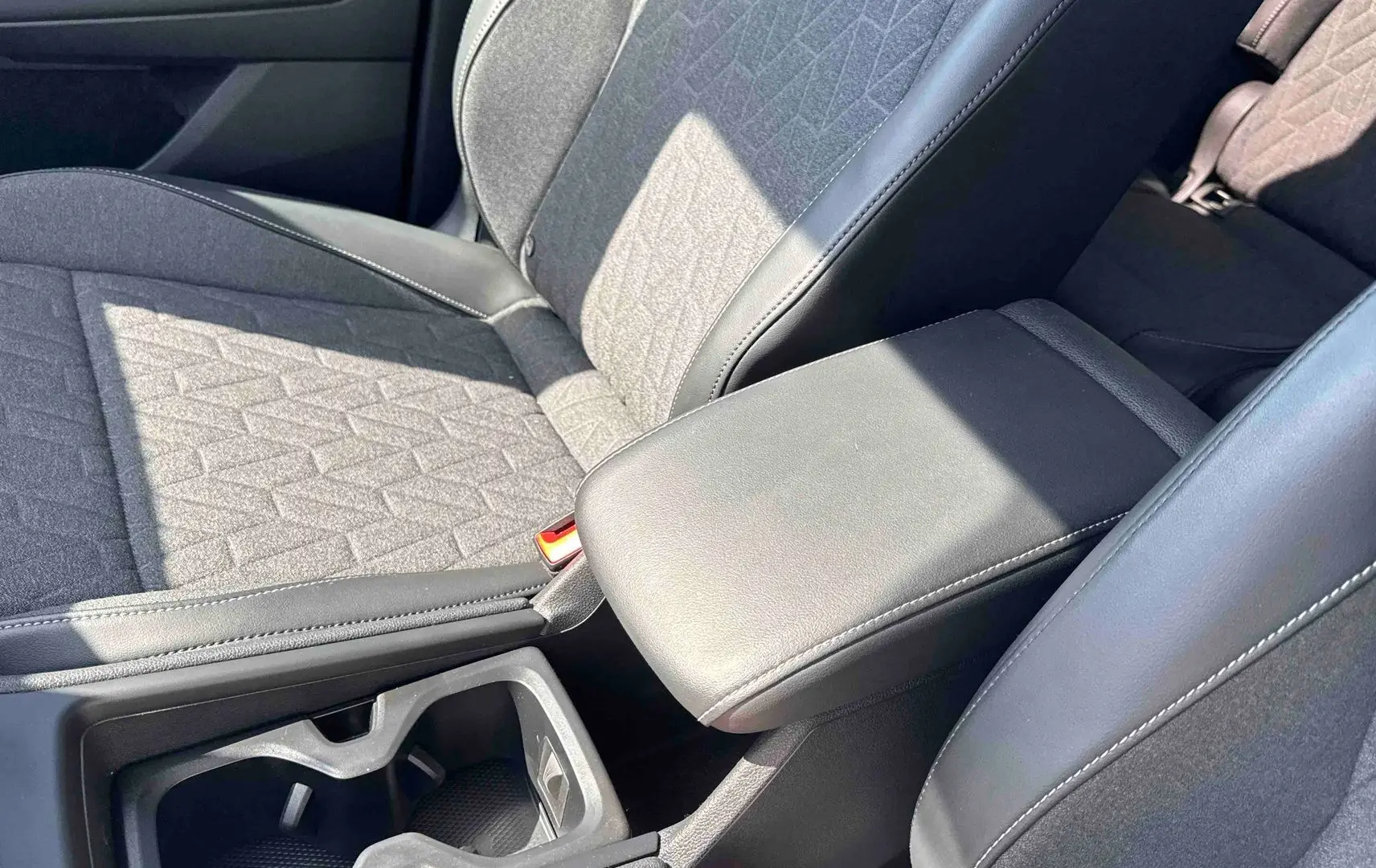 Gros plan sur l'accoudoir central en cuir noir et siège tissu gris du Volkswagen Tiguan 2025, intérieur avant.