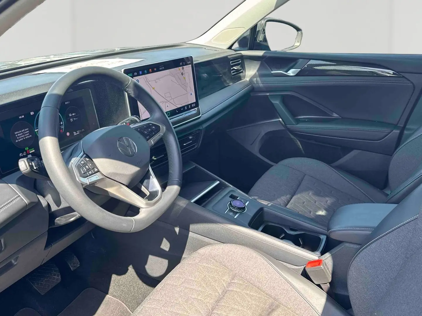 Vue intérieure côté conducteur du Volkswagen Tiguan 2025, tableau de bord moderne avec écran tactile et sièges gris.