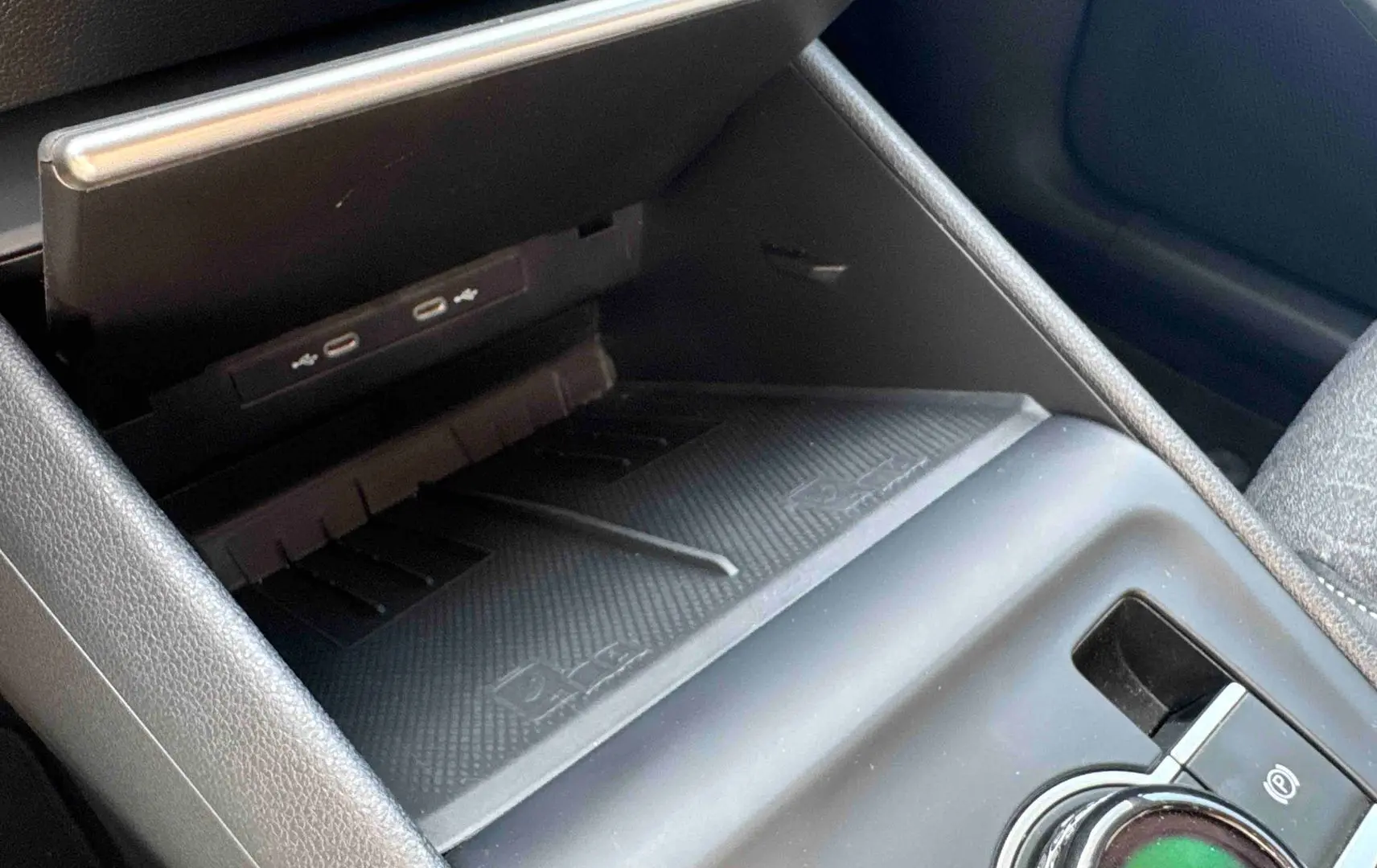Gros plan sur la console centrale du Volkswagen Tiguan 2025, montrant le chargeur sans fil et le frein de stationnement électrique.