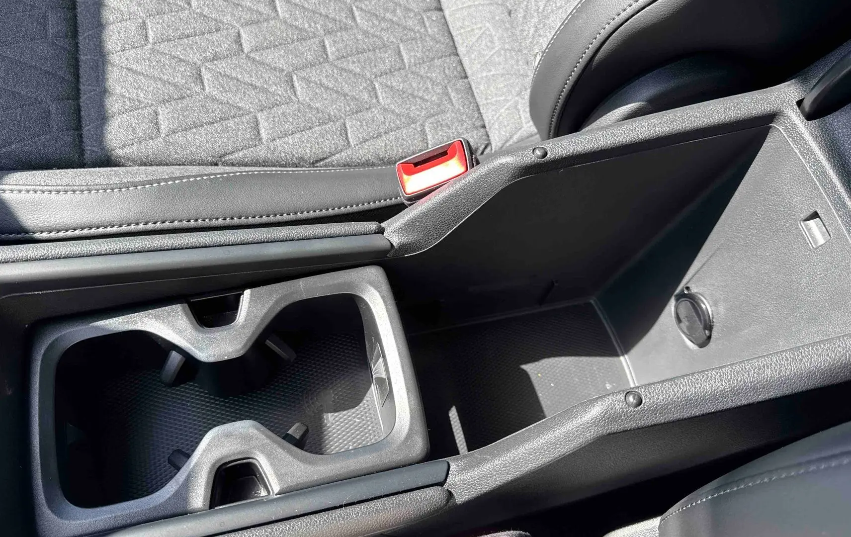 Gros plan sur la console centrale noire avec porte-gobelets et rangement du Volkswagen Tiguan gris 2025.