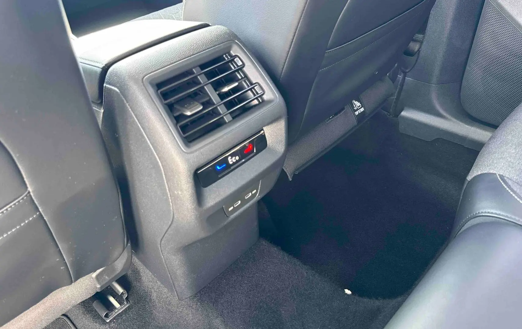 Vue intérieure arrière du Volkswagen Tiguan gris, montrant la console centrale avec bouches d’aération et commandes climatiques Eco.
