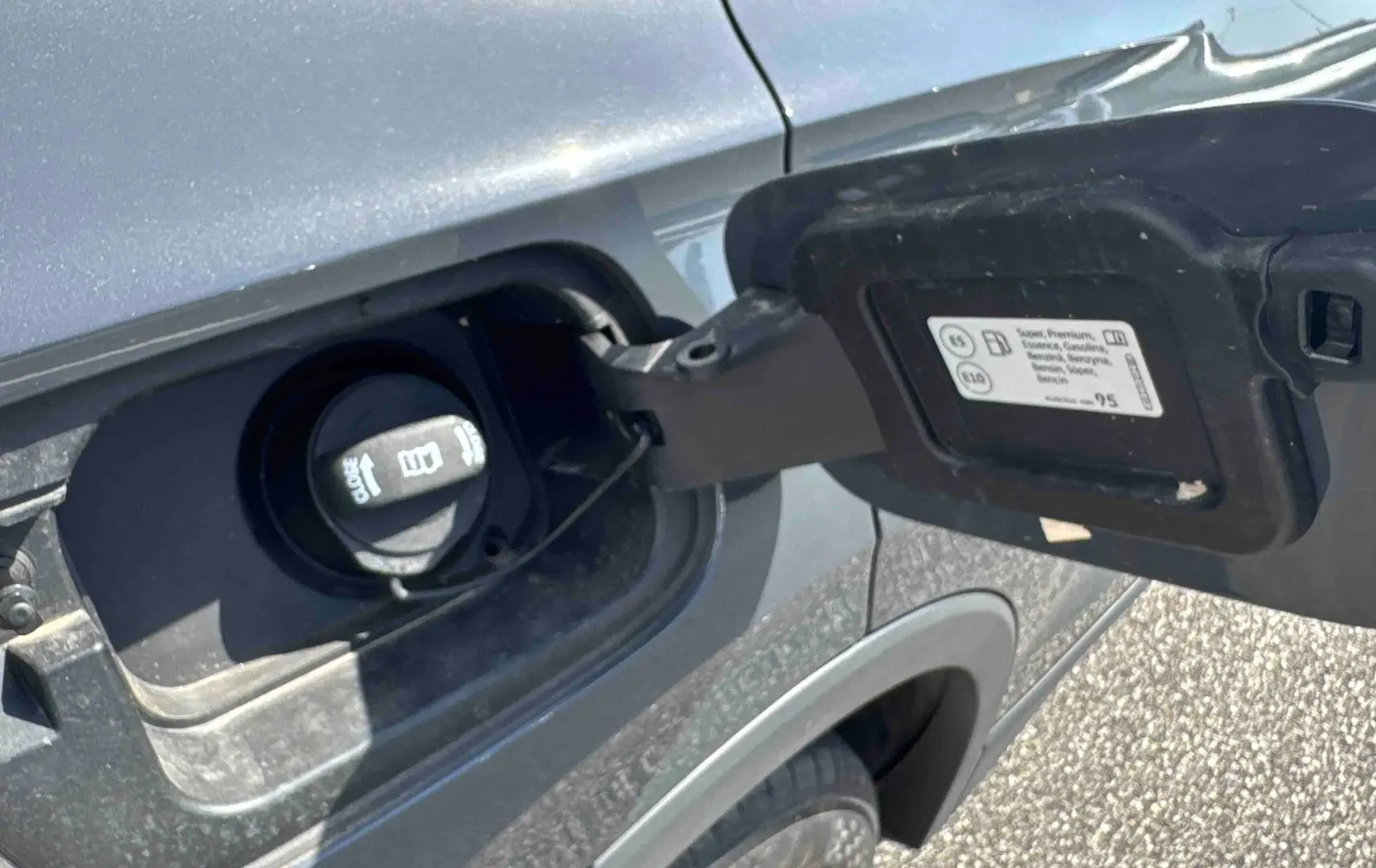 Vue rapprochée de la trappe à carburant côté gauche d’un Volkswagen Tiguan gris 2025 avec bouchon ouvert.