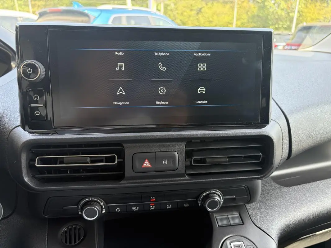 Tableau de bord du Peugeot Partner blanc 2026 avec écran tactile GPS et commandes de climatisation visibles de face.