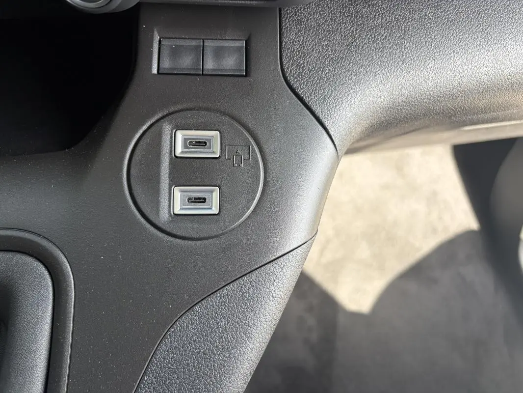 Gros plan sur les deux ports USB-C intégrés dans la console centrale noire du Peugeot Partner blanc.
