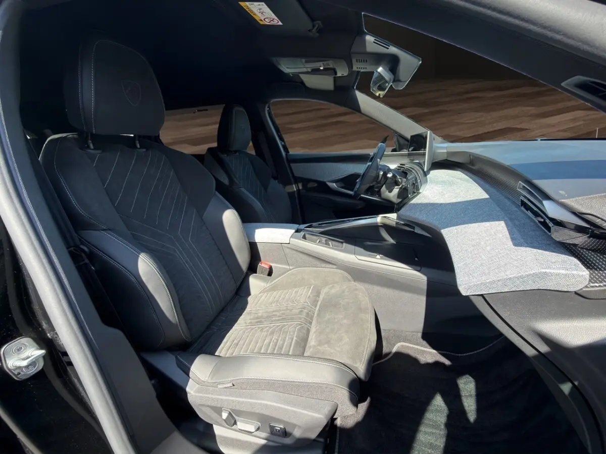 Vue intérieure côté conducteur du Peugeot 5008 2025 noir, mettant en valeur la sellerie Alcantara et le tableau de bord moderne.
