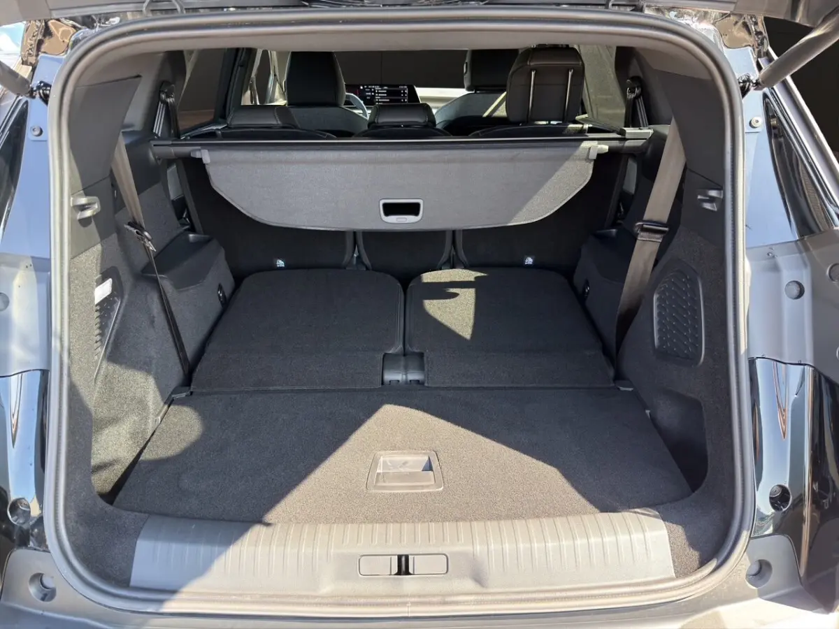 Coffre ouvert d’un Peugeot 5008 noir, vue arrière montrant les sièges rabattus et la tablette cache-bagages.