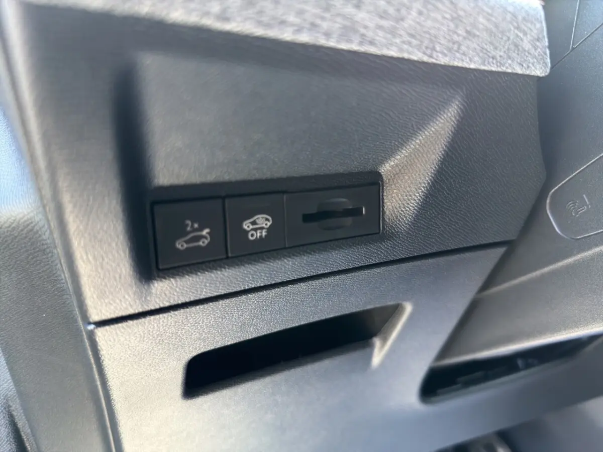 Détail des commandes d'ouverture du coffre et désactivation d'assistance sur tableau de bord noir intérieur Peugeot 5008 hybride.