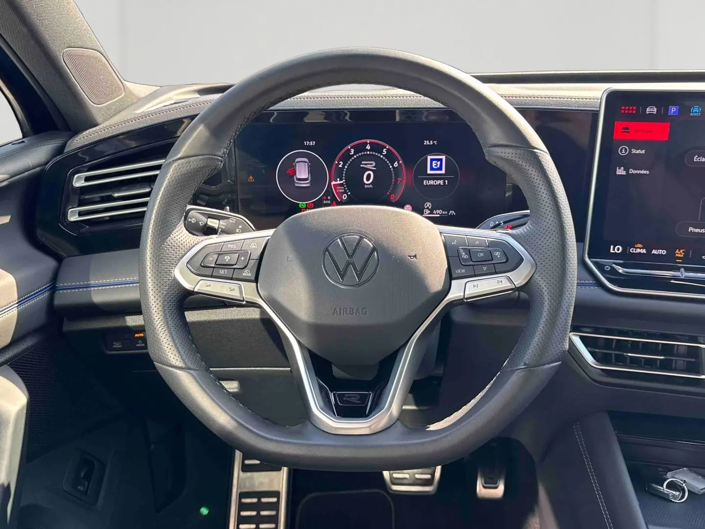 Vue intérieure centrée sur le volant multifonction cuir du Volkswagen Tiguan 2025 avec tableau de bord digital et écran tactile.