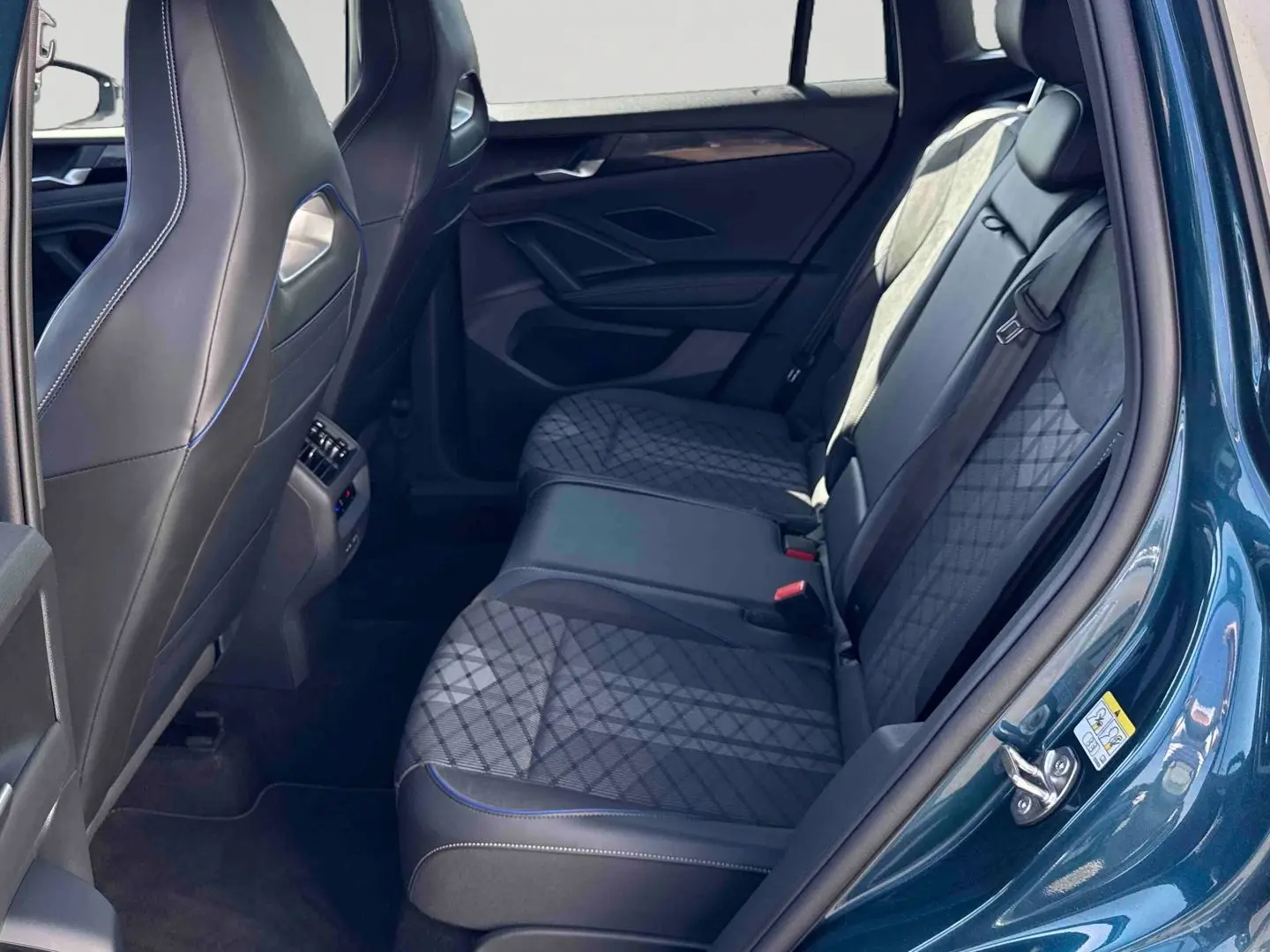 Vue intérieure côté droit sur la banquette arrière du Volkswagen Tiguan 2025 bleu avec sièges en tissu et cuir noir.