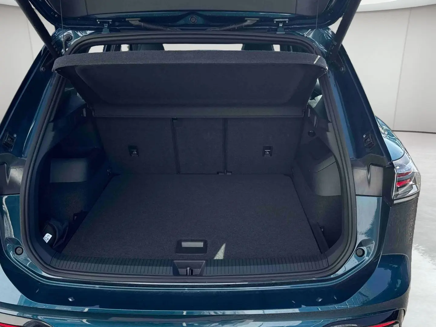 Coffre ouvert vu de l'arrière d'un Volkswagen Tiguan 2025 bleu, montrant l'espace de chargement vide et le hayon relevé.