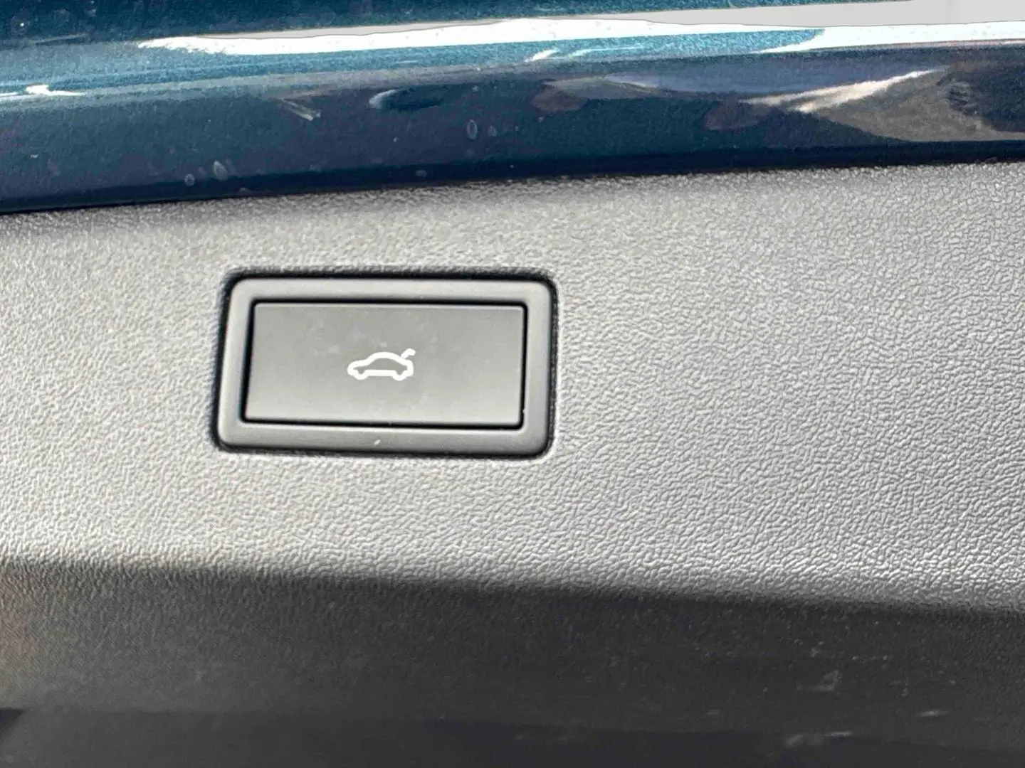 Bouton d'ouverture électrique du hayon sur panneau intérieur bleu du Volkswagen Tiguan 2025.