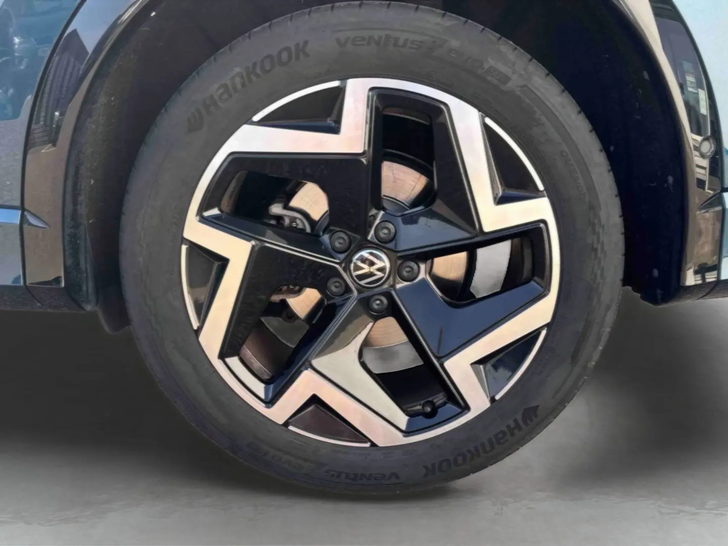 Gros plan sur la jante alliage 19 pouces bicolore du Volkswagen Tiguan bleu, côté avant droit.