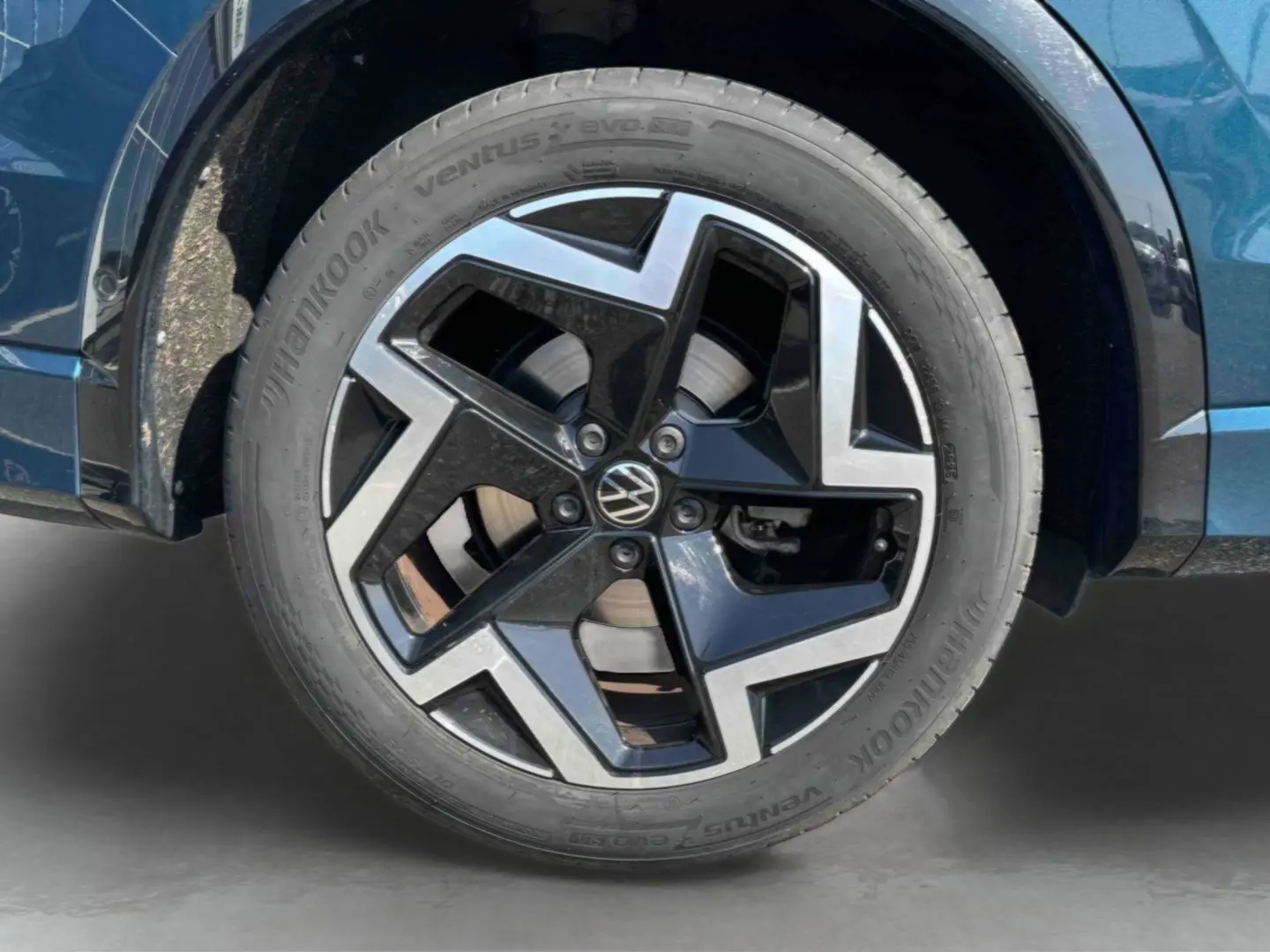 Gros plan sur la jante alliage 19 pouces bicolore du Volkswagen Tiguan bleu, avec pneu Hankook visible.