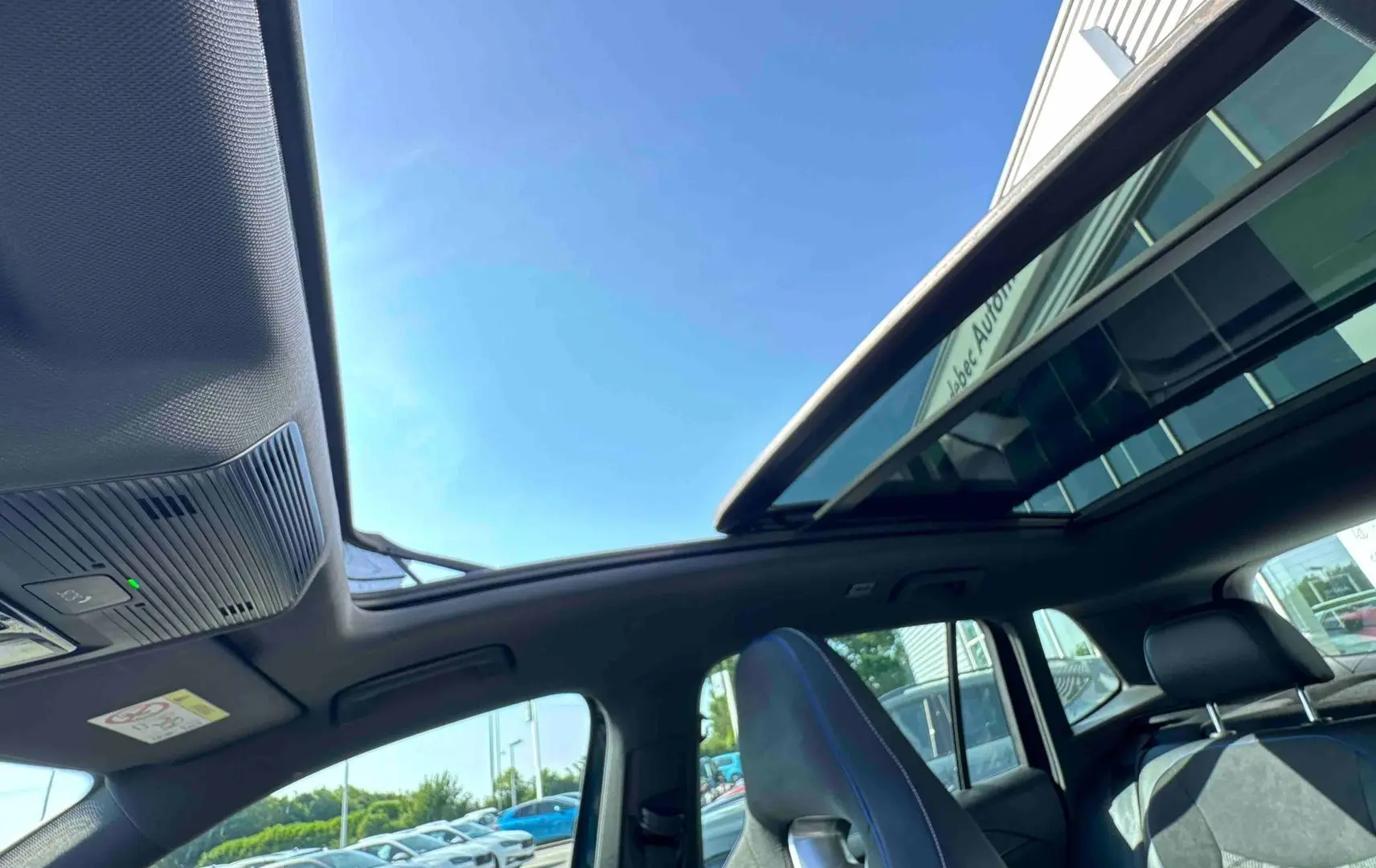 Vue intérieure du toit ouvrant panoramique et des sièges avant noirs du Volkswagen Tiguan bleu 2025.