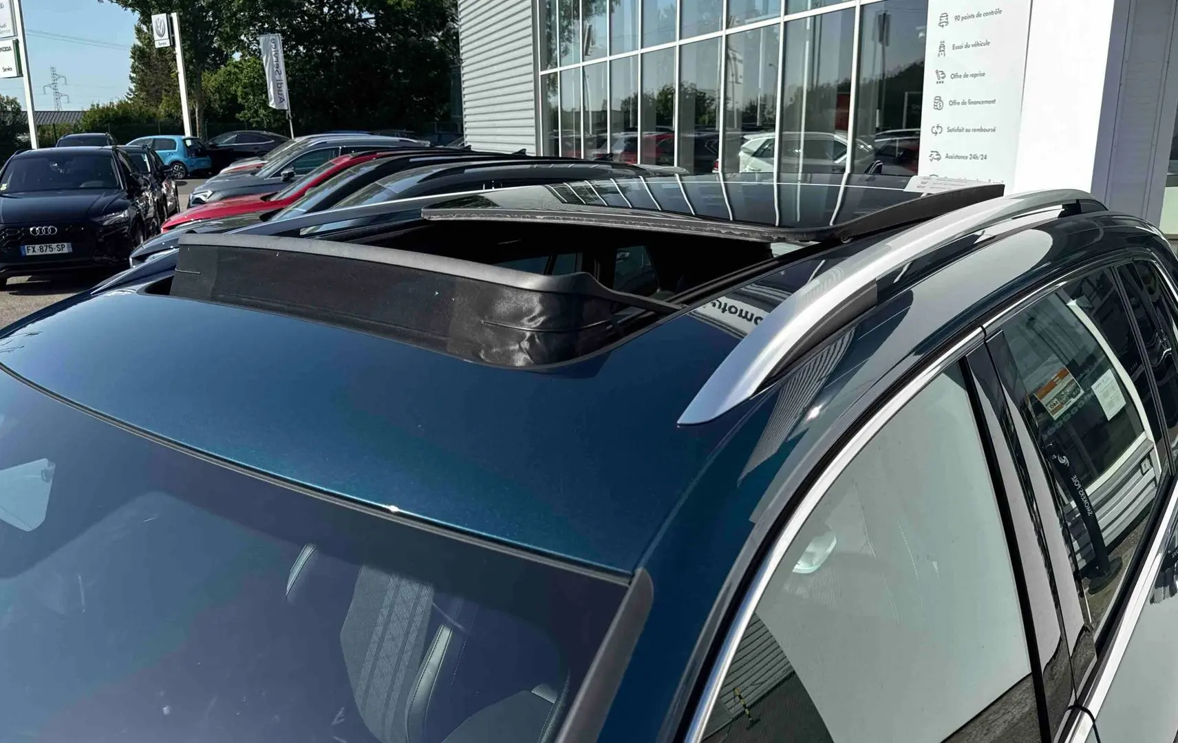 Toit ouvrant panoramique ouvert sur le côté gauche d’un Volkswagen Tiguan bleu 2025 en extérieur.