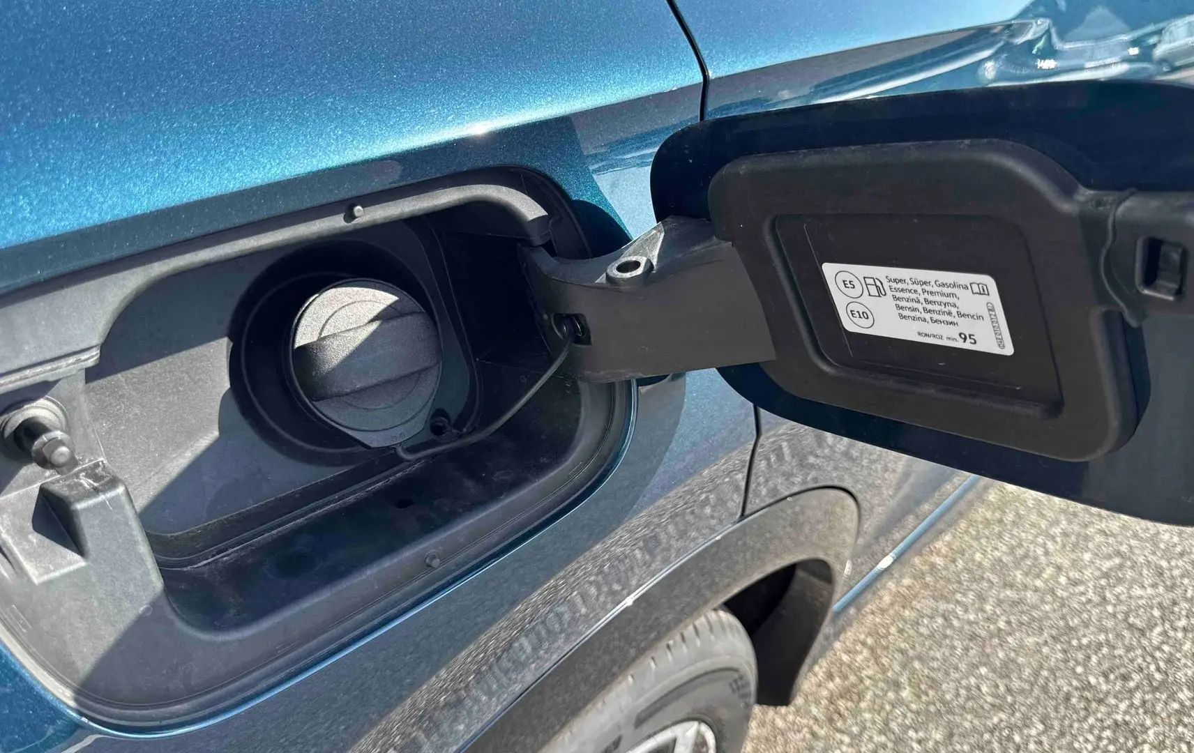 Gros plan sur la trappe à carburant ouverte côté gauche d’un Volkswagen Tiguan bleu 2025.
