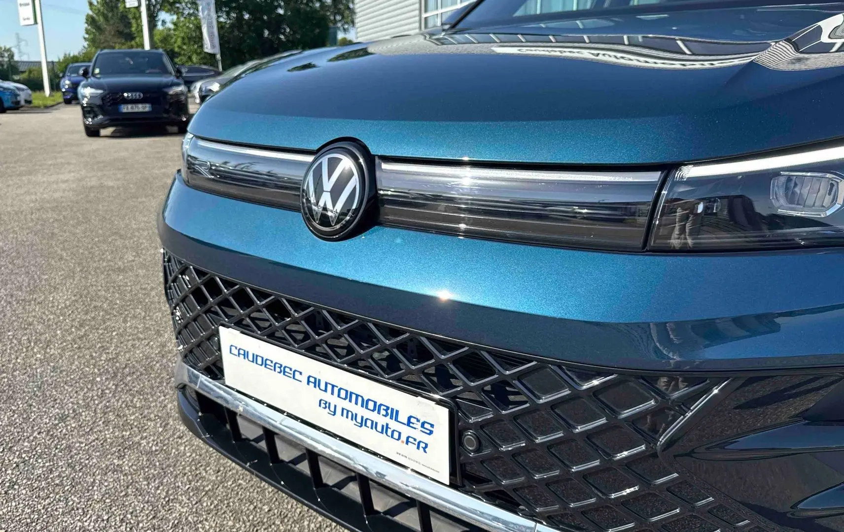 Vue avant rapprochée du Volkswagen Tiguan bleu avec calandre ajourée et logo VW centré brillant.