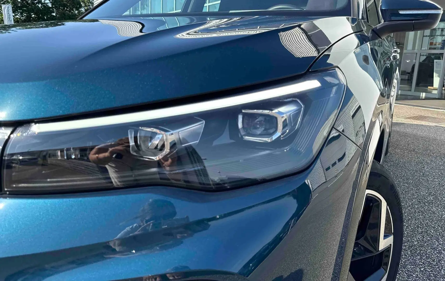 Gros plan sur le phare avant droit et la jante alliage 19 pouces du Volkswagen Tiguan bleu 2025.