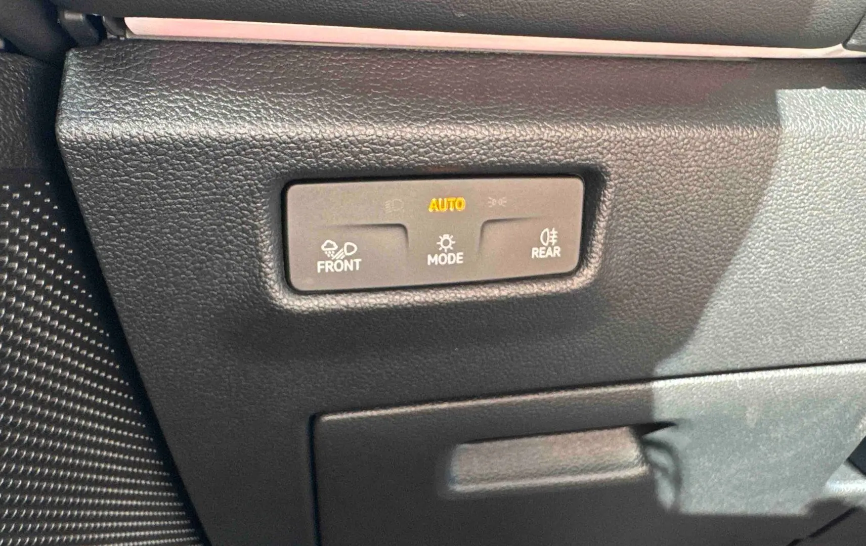 Gros plan sur les commandes d’éclairage automatiques du Volkswagen Tiguan 2025, finition R-Line, intérieur noir.