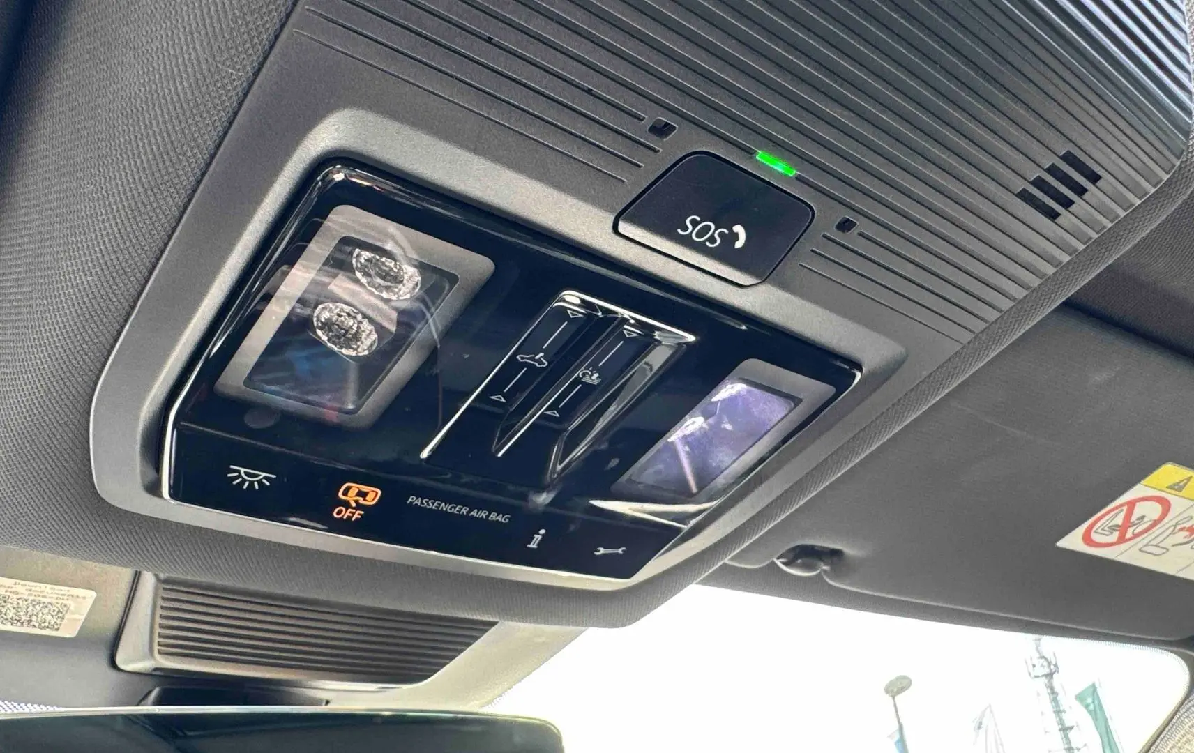 Vue intérieure en gros plan du plafonnier avec commandes d’éclairage et bouton SOS du Volkswagen Tiguan bleu 2025.
