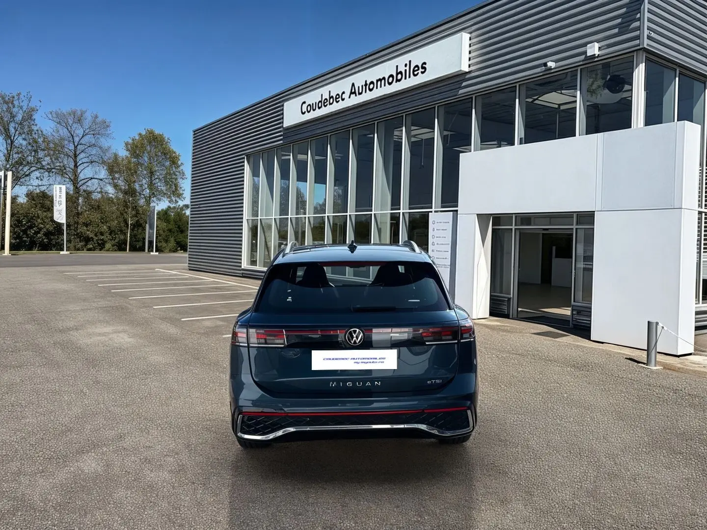 Vue arrière d'un Volkswagen Tiguan 2025 bleu garé devant un showroom Coudebec Automobiles.