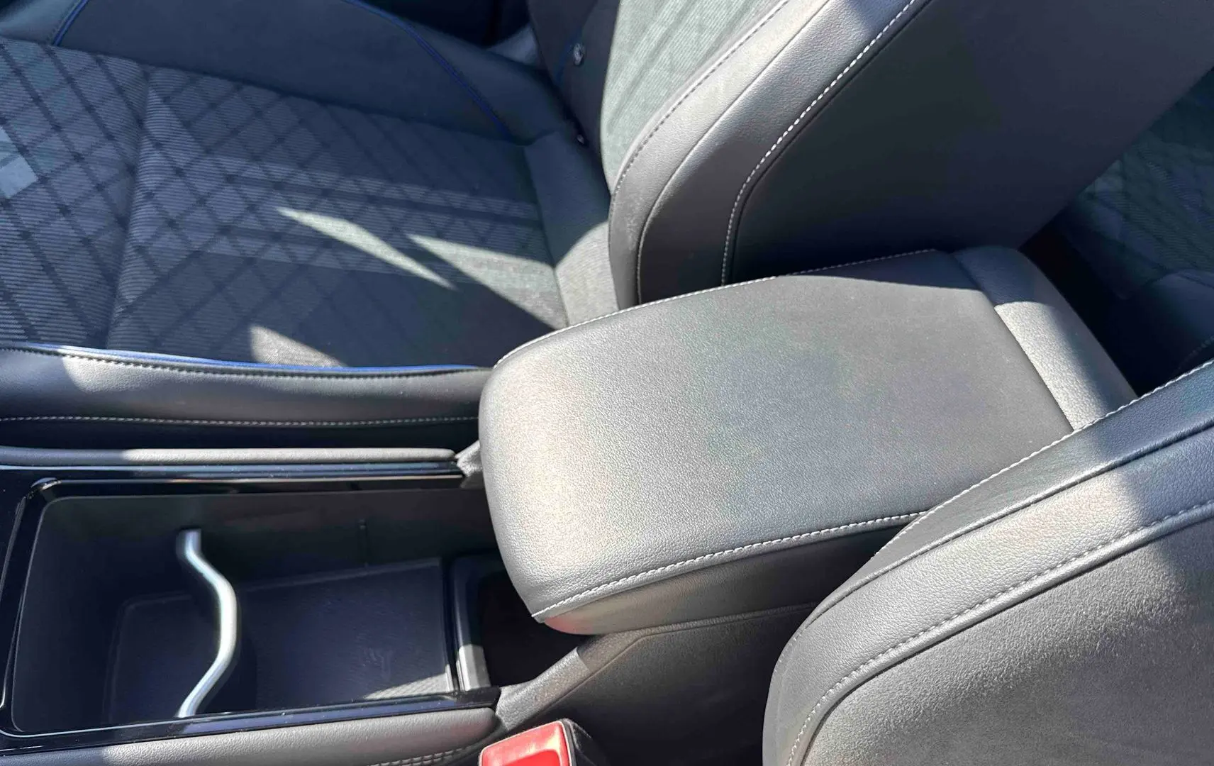 Gros plan sur l'accoudoir central en cuir noir et la console entre les sièges avant du Volkswagen Tiguan.