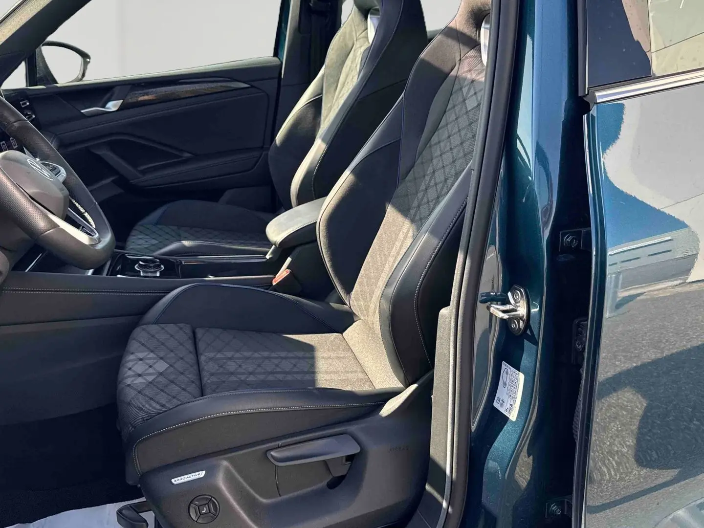 Vue intérieure côté gauche du Volkswagen Tiguan 2025 bleu, mettant en valeur les sièges avant sport en tissu et cuir.