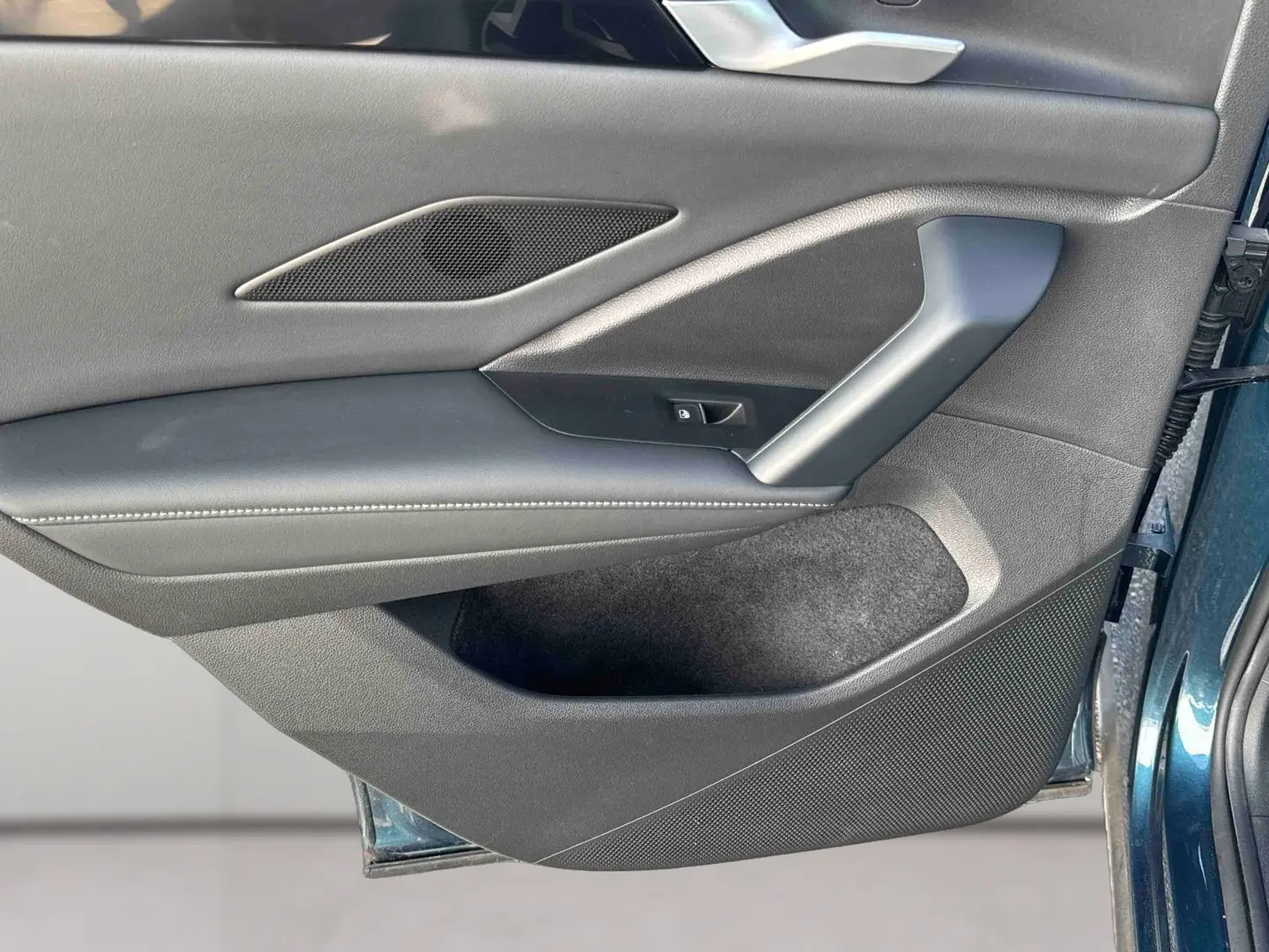 Vue rapprochée de la porte avant gauche du Volkswagen Tiguan 2025 bleu, montrant la garniture intérieure noire et les commandes.