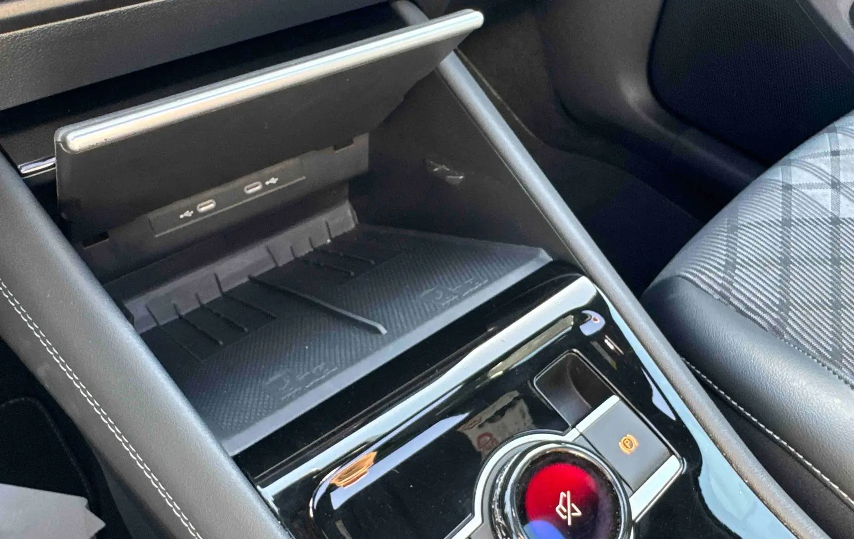 Gros plan sur la console centrale intérieure du Volkswagen Tiguan 2025, avec chargeur sans fil et frein de stationnement électronique.