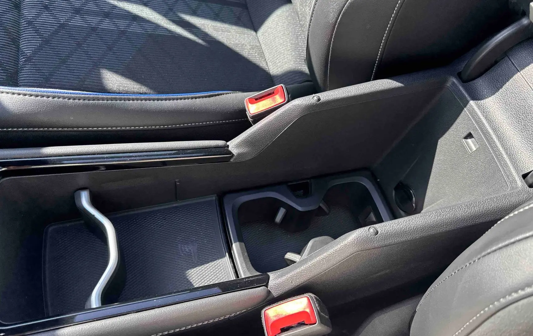 Gros plan sur la console centrale noire du Volkswagen Tiguan 2025, avec porte-gobelets et accoudoir en cuir.