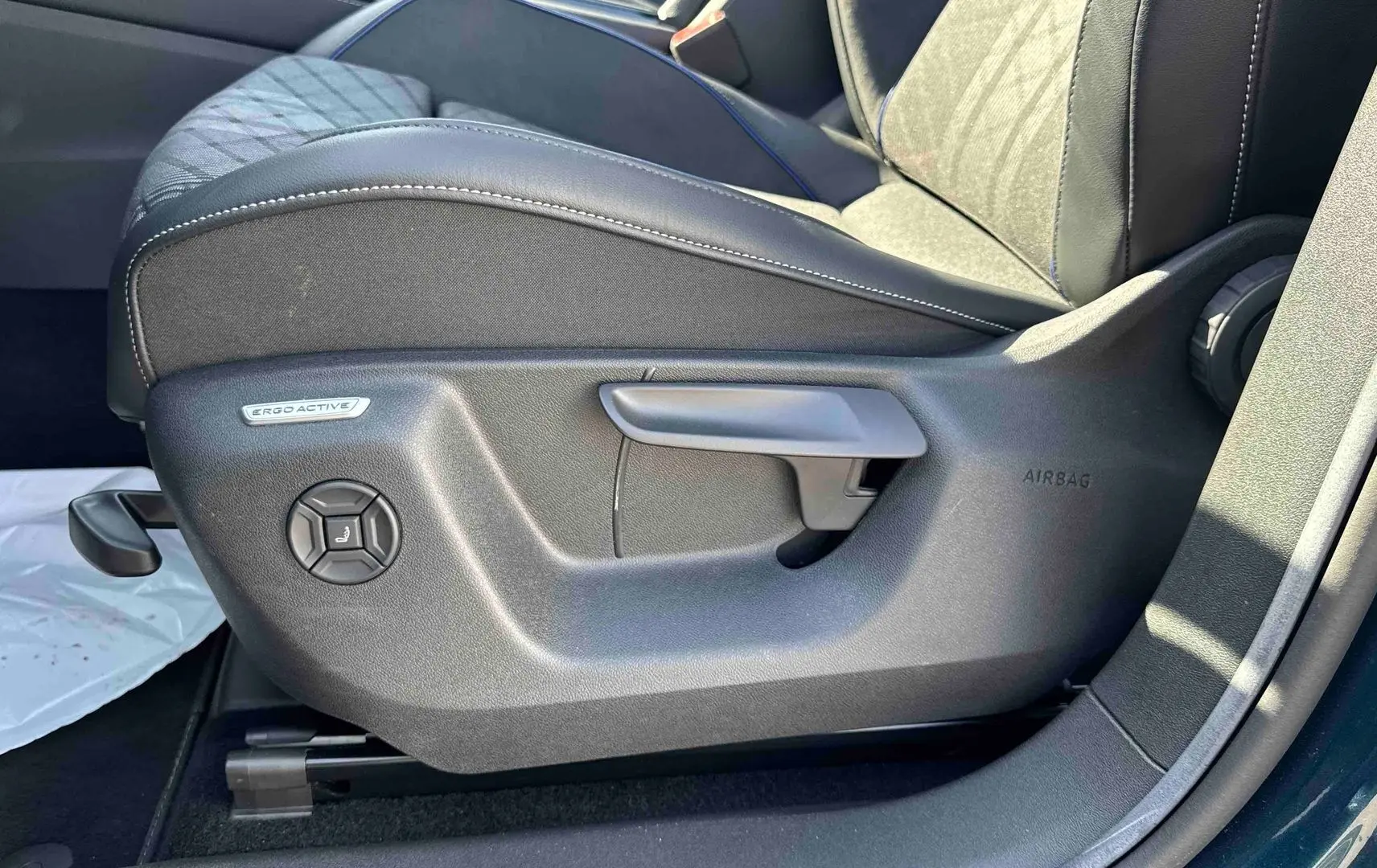 Détail du siège conducteur ErgoActive avec réglages manuels sur le côté gauche d’un Volkswagen Tiguan bleu.