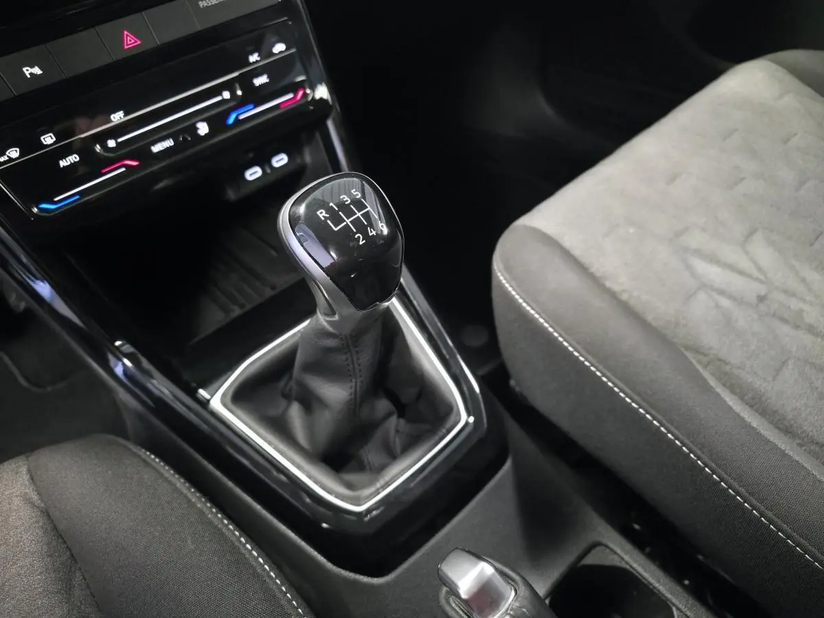 Gros plan sur le levier de vitesses manuel noir et la sellerie grise du Volkswagen T-Cross 1.0 TSI Life 2025.