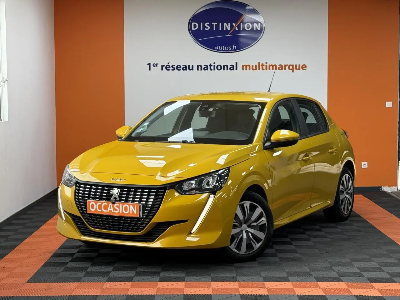 Peugeot 208 jaune clair vue 3/4 avant avec calandre noire et jantes 16 pouces en intérieur showroom.