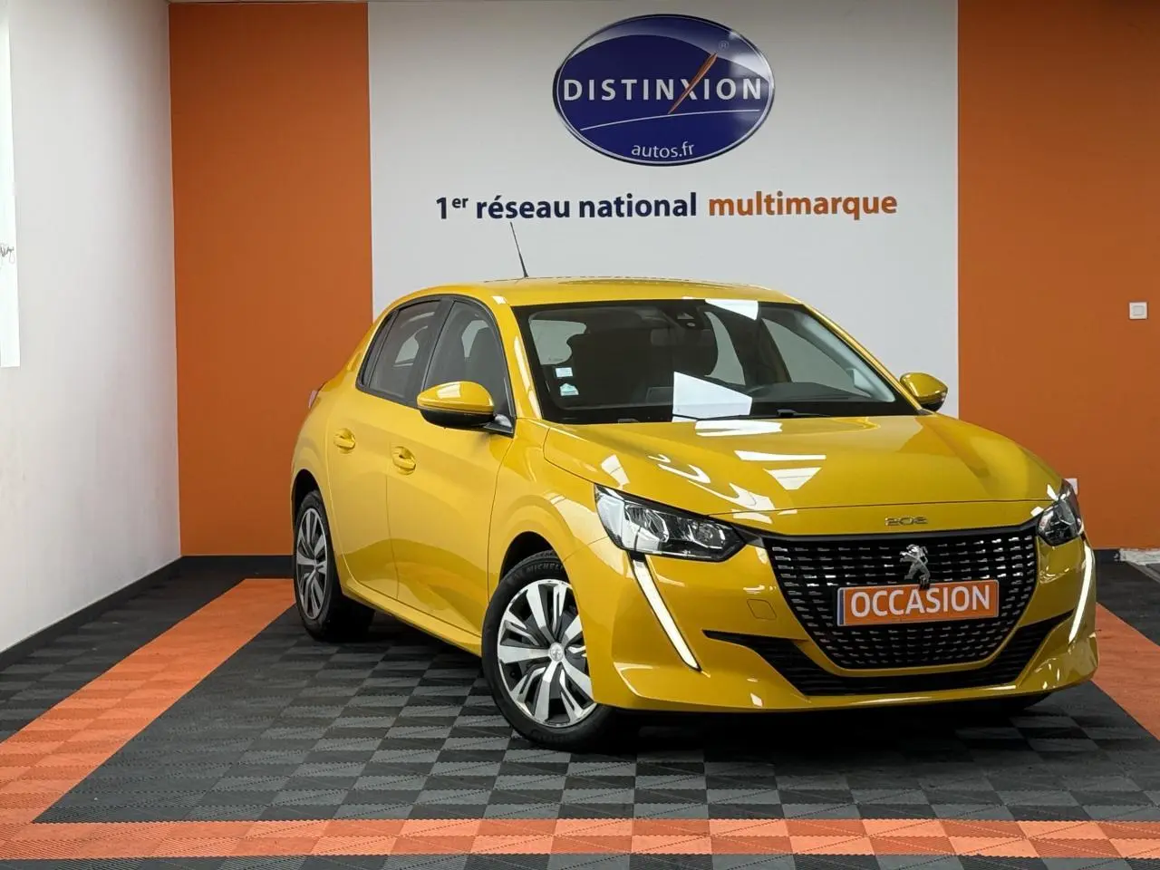 Peugeot 208 jaune clair vue 3/4 avant droit, avec calandre noire et jantes 16 pouces en tôle avec enjoliveurs.