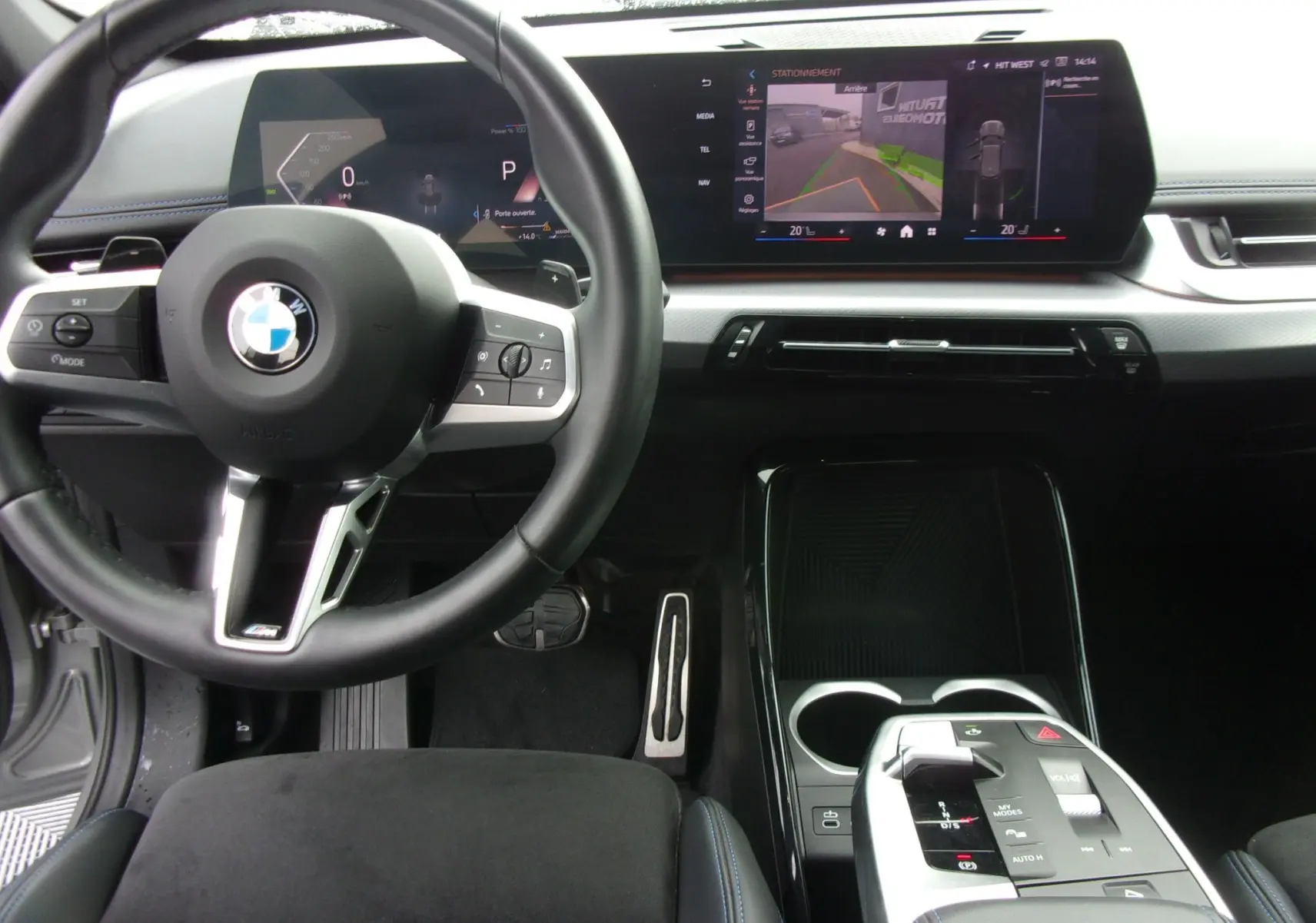 Vue intérieure avant du BMW X1 2024 M Sport avec volant cuir noir, écran digital large et console centrale moderne.