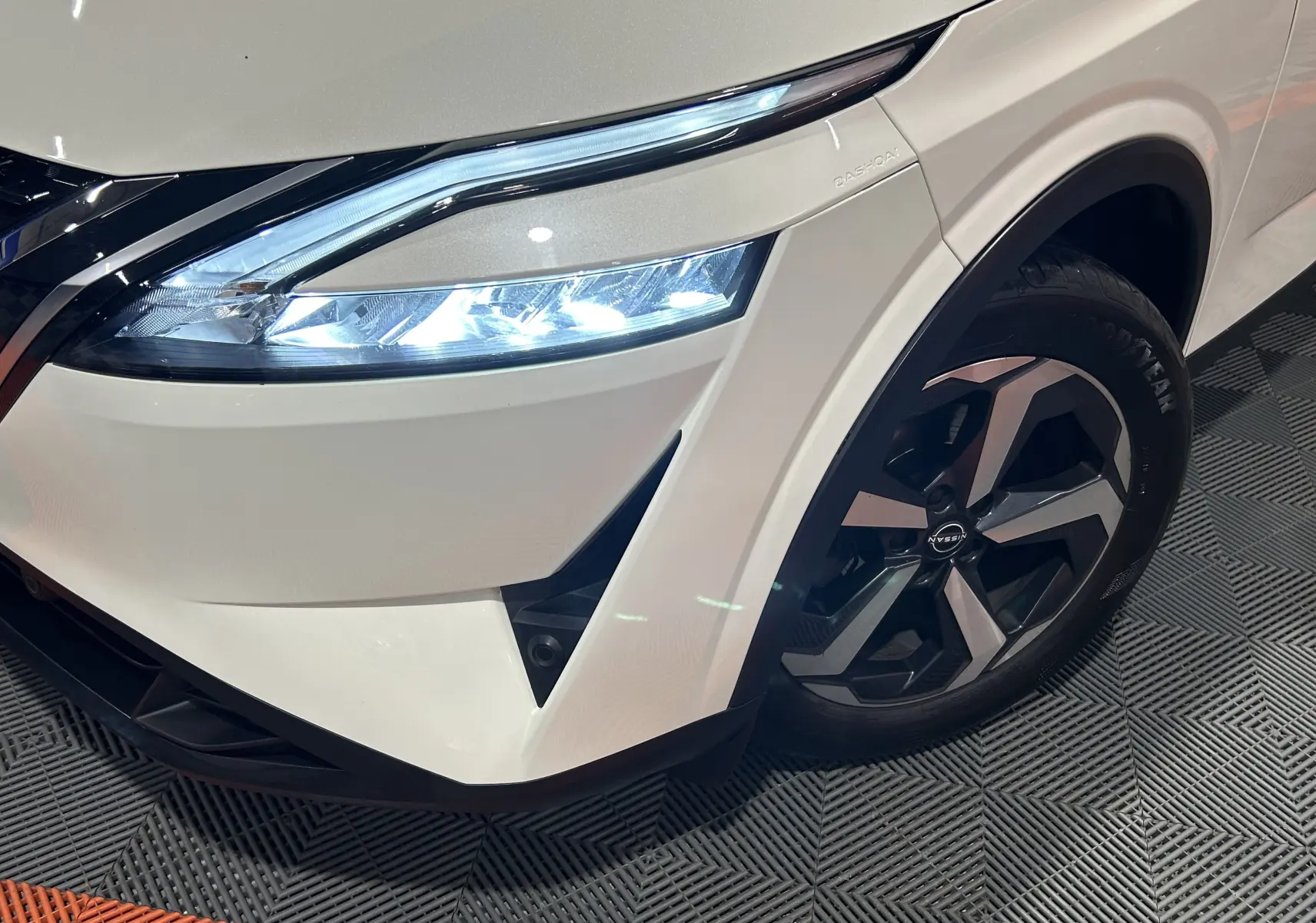 Gros plan sur l’avant droit du Nissan Qashqai blanc lunaire, mettant en valeur le phare LED et la jante alliage.