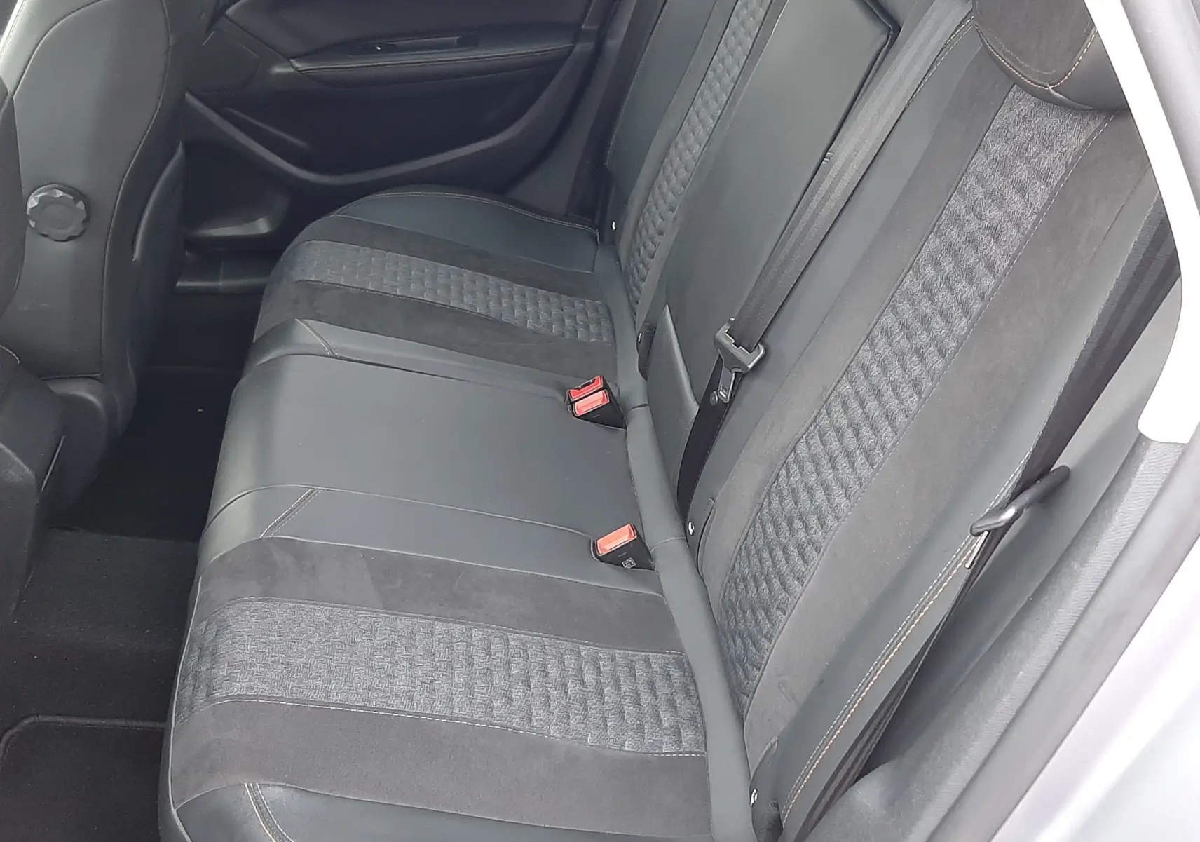 Vue intérieure côté droit des sièges arrière en tissu et cuir noir avec surpiqûres orange d'une Peugeot 308 SW gris Artense.