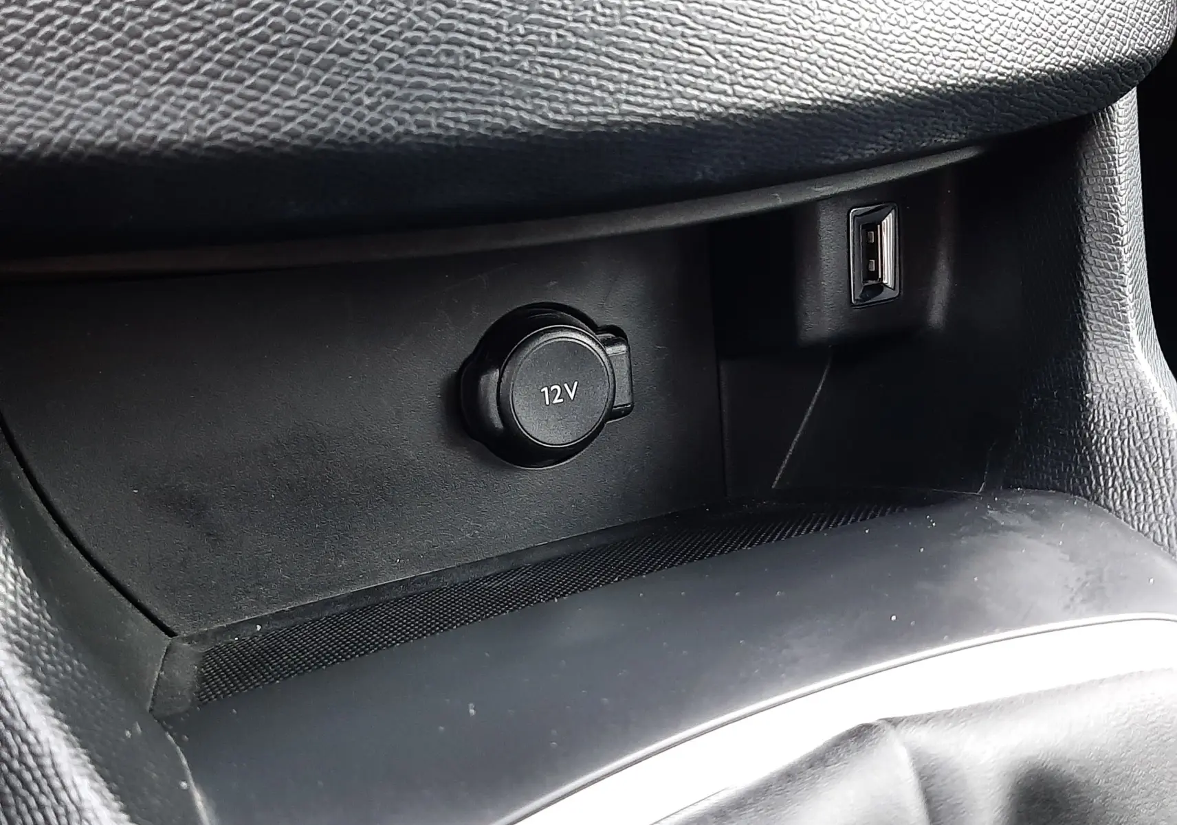Gros plan intérieur sur la prise 12V et port USB dans la console centrale noire du Peugeot 308 SW gris Artense.