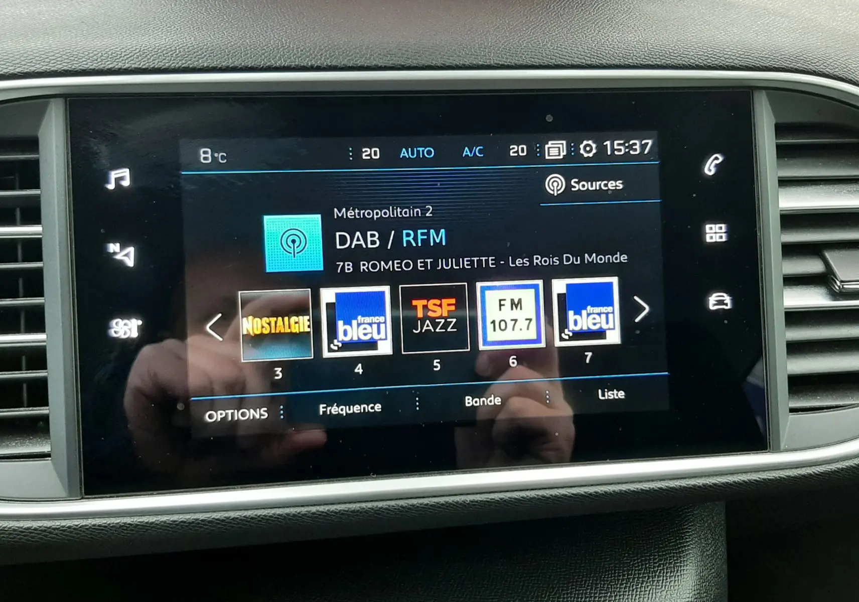 Écran central tactile de la Peugeot 308 SW gris Artense affichant les stations radio DAB en intérieur.