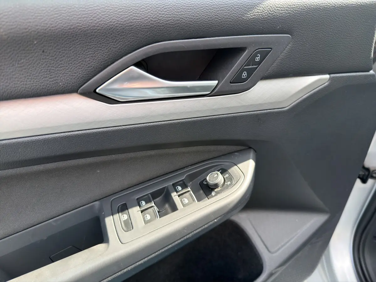 Détail de la porte côté conducteur de la Volkswagen Golf 2022 gris clair, avec commandes des vitres et serrure intégrée.
