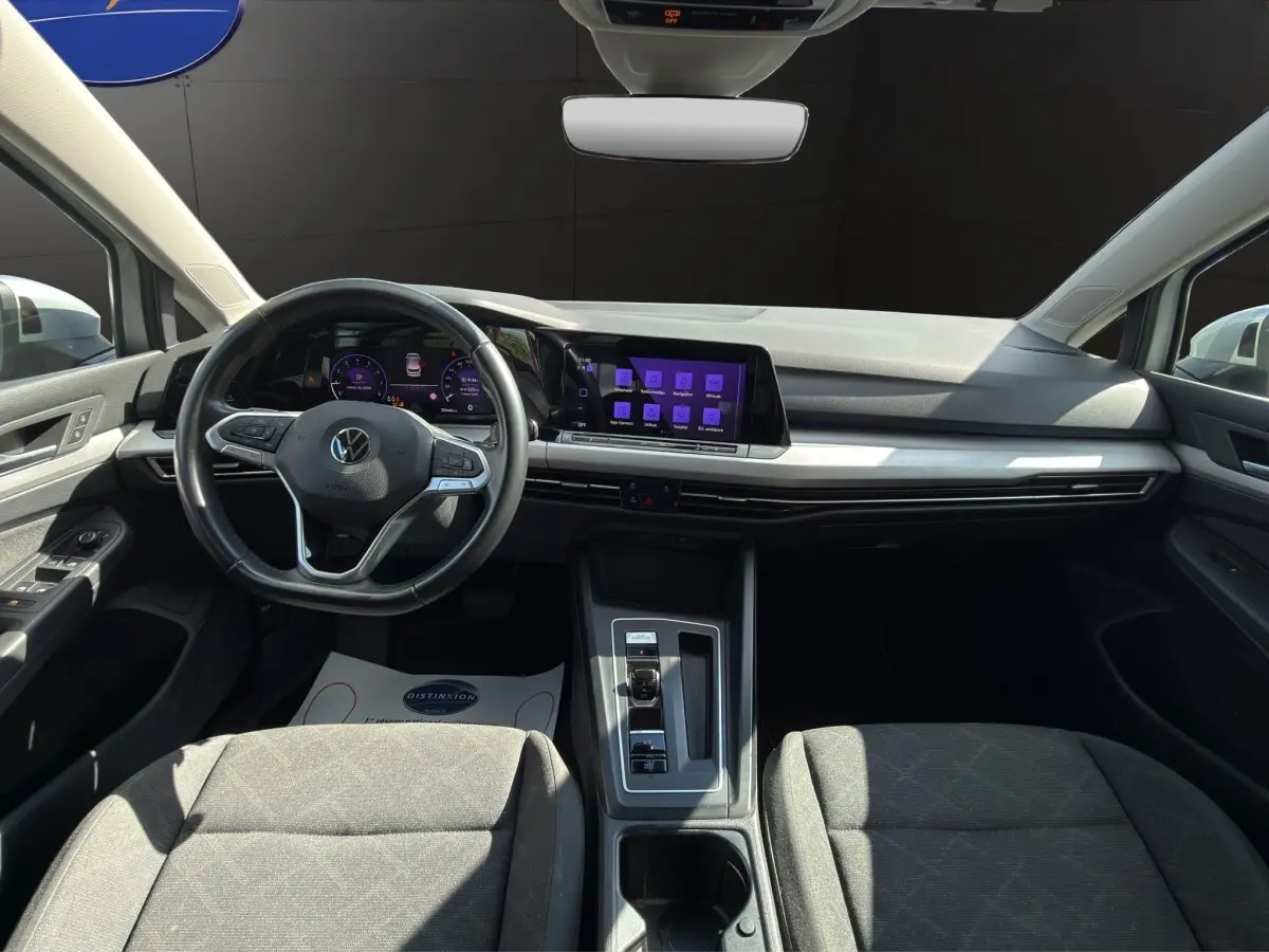 Vue intérieure avant de la Volkswagen Golf 1.0 ETSI gris clair, avec tableau de bord numérique et écran tactile central.