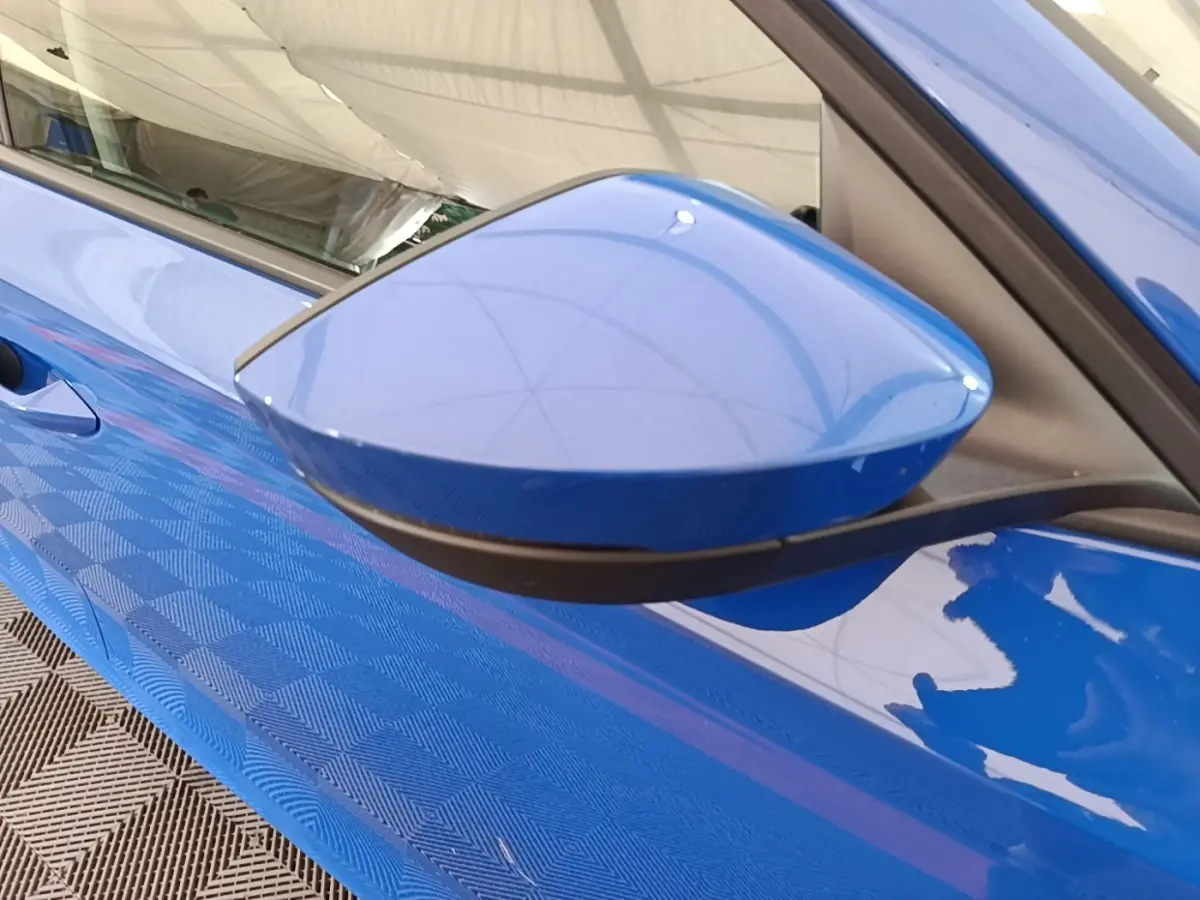 Rétroviseur côté gauche bleu vif de la Skoda Octavia 2024, avec portière et poignée partiellement visibles.
