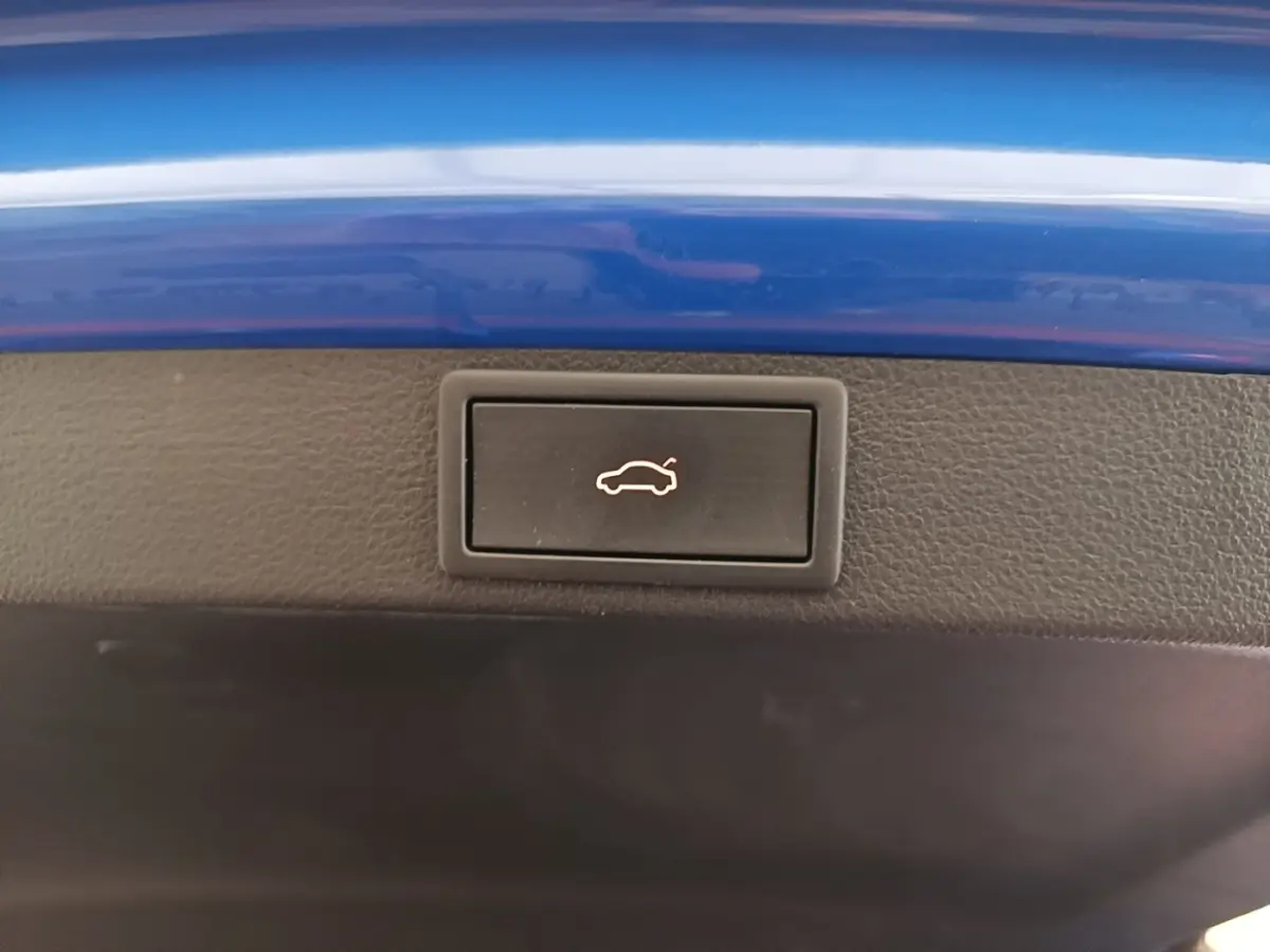 Bouton d'ouverture du coffre sur la bordure intérieure d'une Skoda Octavia 2024 bleu électrique.