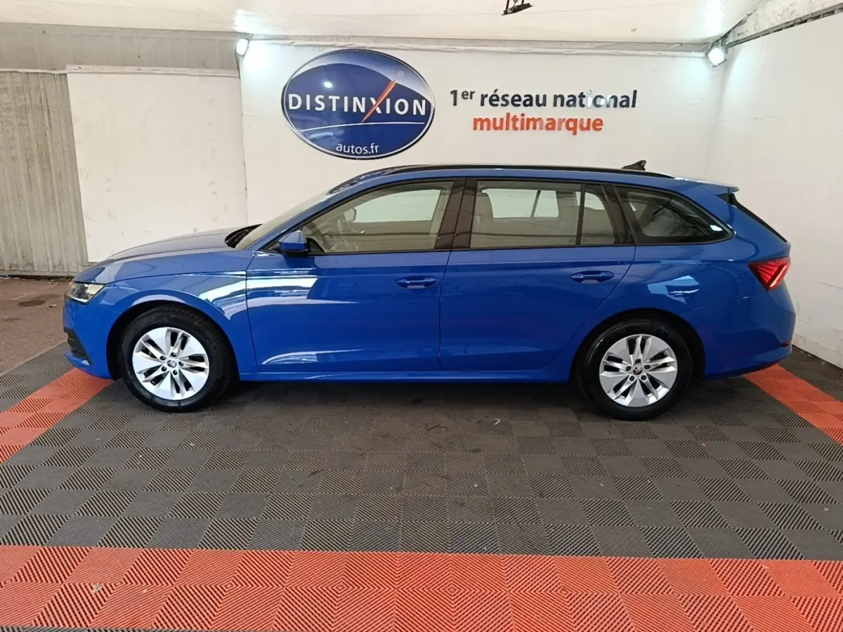 Vue de profil côté gauche d'une Skoda Octavia break 2024 bleu vif, avec jantes alliage et rails de toit noirs.