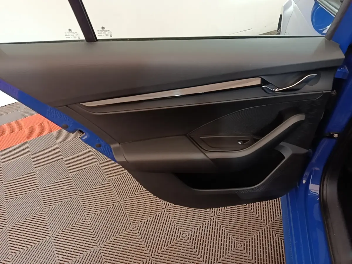 Vue intérieure de la porte avant gauche bleue d'une Skoda Octavia 2024 avec garniture noire et poignée chrome.
