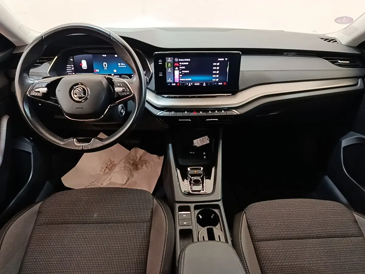 Vue intérieure avant de la Skoda Octavia 2024, tableau de bord noir avec écran tactile central et volant multifonctions.